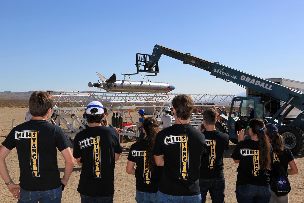 MOJAVE DESERT, Calif. – In the Mojave Desert in California, students from Merritt Island High School in Florida watch as the Garvey Spacecraft Corporation's Prospector P-18D rocket is lifted into position for its scheduled launch on June 15 with the RUBICS-1 payload on a high-altitude, suborbital flight. The rocket will carry four satellites made from four-inch cube sections, one developed by students from the school that is located near the Kennedy Space Center. Collectively known as CubeSats, the satellites will record shock, vibrations and heat inside the rocket. They will not be released during the test flight, but the results will be used to prove or strengthen their designs before they are carried into orbit in 2014 on a much larger rocket. A new, lightweight carrier is also being tested for use on future missions to deploy the small spacecraft. The flight also is being watched closely as a model for trying out new or off-the-shelf technologies quickly before putting them in the pipeline for use on NASA's largest launchers. Built by several different organizations, including a university, a NASA field center and a high school, the spacecraft are four-inch cubes designed to fly on their own eventually, but will remain firmly attached to the rocket during the upcoming mission. For more information, visit http://www.nasa.gov/mission_pages/smallsats/elana/cubesatlaunchpreview.html Photo credit: NASA/Dimitri Gerondidakis