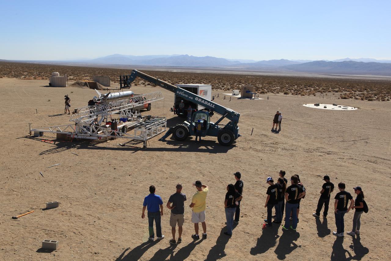 MOJAVE DESERT, Calif. – In the Mojave Desert in California, students from Merritt Island High School in Florida watch as the Garvey Spacecraft Corporation's Prospector P-18D rocket is lifted into position for its scheduled launch on June 15 with the RUBICS-1 payload on a high-altitude, suborbital flight. The rocket will carry four satellites made from four-inch cube section, one developed by students from the school that is located near the Kennedy Space Center. Collectively known as CubeSats, the satellites will record shock, vibrations and heat inside the rocket. They will not be released during the test flight, but the results will be used to prove or strengthen their designs before they are carried into orbit in 2014 on a much larger rocket. A new, lightweight carrier is also being tested for use on future missions to deploy the small spacecraft. The flight also is being watched closely as a model for trying out new or off-the-shelf technologies quickly before putting them in the pipeline for use on NASA's largest launchers. Built by several different organizations, including a university, a NASA field center and a high school, the spacecraft are four-inch cubes designed to fly on their own eventually, but will remain firmly attached to the rocket during the upcoming mission. For more information, visit http://www.nasa.gov/mission_pages/smallsats/elana/cubesatlaunchpreview.html Photo credit: NASA/Dimitri Gerondidakis