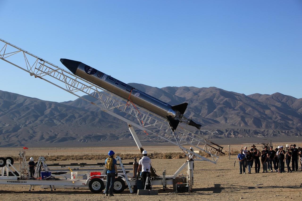 MOJAVE DESERT, Calif. – In the Mojave Desert in California, students and engineers watch as the Garvey Spacecraft Corporation's Prospector P-18D rocket is lifted into position for its scheduled launch on June 15 with the RUBICS-1 payload on a high-altitude, suborbital flight. The rocket will carry four satellites made from four-inch cube sections. Collectively known as CubeSats, the satellites will record shock, vibrations and heat inside the rocket. They will not be released during the test flight, but the results will be used to prove or strengthen their designs before they are carried into orbit in 2014 on a much larger rocket. A new, lightweight carrier is also being tested for use on future missions to deploy the small spacecraft. The flight also is being watched closely as a model for trying out new or off-the-shelf technologies quickly before putting them in the pipeline for use on NASA's largest launchers. Built by several different organizations, including a university, a NASA field center and a high school, the spacecraft are four-inch cubes designed to fly on their own eventually, but will remain firmly attached to the rocket during the upcoming mission. For more information, visit http://www.nasa.gov/mission_pages/smallsats/elana/cubesatlaunchpreview.html Photo credit: NASA/Dimitri Gerondidakis