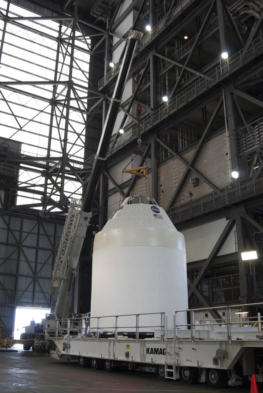 CAPE CANAVERAL, Fla. -- In the transfer aisle of the Vehicle Assembly Building at NASA’s Kennedy Space Center in Florida, a full-size test mock-up of the Orion spacecraft has been lowered onto a transporter. Crane operators and technicians practice de-stacking operations on mock-ups of the Orion spacecraft and launch abort system in order to keep processing procedures and skills current. Orion is the exploration spacecraft designed to carry crews to space beyond low Earth orbit. It will provide emergency abort capability, sustain the crew during the space travel and provide safe re-entry from deep space return velocities. Orion’s first unpiloted test flight is scheduled to launch in 2014 atop a Delta IV rocket. A second uncrewed flight test is scheduled for 2017 on NASA’s Space Launch System rocket. For more information, visit http://www.nasa.gov/orion. Photo credit: NASA/Tim Jacobs