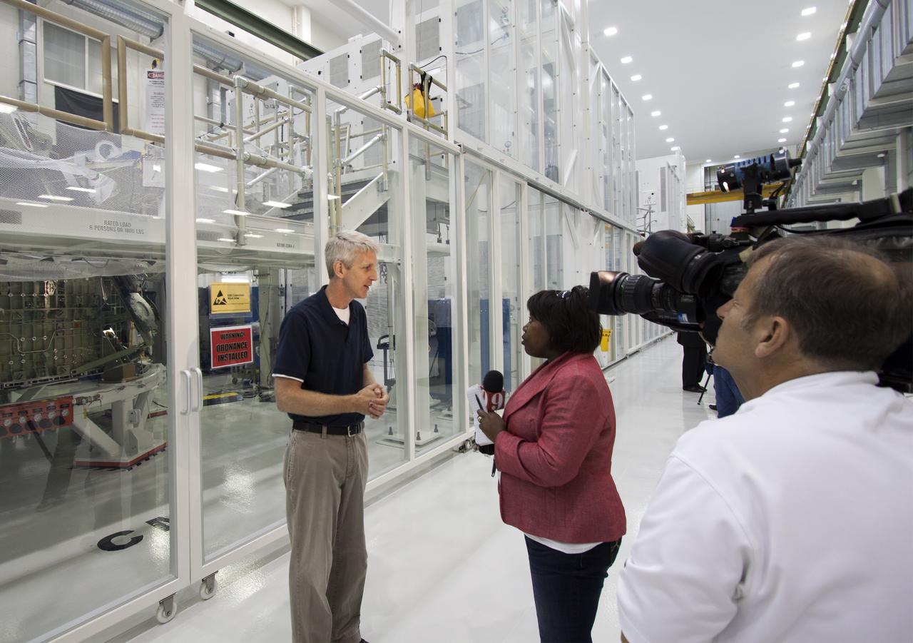 CAPE CANAVERAL, Fla. – Inside the Operations and Checkout Building high bay at NASA’s Kennedy Space Center in Florida, members of the media receive an on activities in NASA’s Ground Systems Development and Operations, or GSDO, Program, Space Launch System and Orion crew module for Exploration Test Flight 1. Speaking to the media is Scott Wilson, manager of Orion Production Operations at Kennedy. In the background is a clean room that contains the Orion crew module.    Orion is the exploration spacecraft designed to carry crews to space beyond low Earth orbit. It will provide emergency abort capability, sustain the crew during the space travel and provide safe re-entry from deep space return velocities. Orion’s first unpiloted test flight is scheduled to launch in 2014 atop a Delta IV rocket. A second uncrewed flight test is scheduled for 2017 on NASA’s Space Launch System rocket. For more information, visit http://www.nasa.gov/orion. Photo credit: NASA/Jim Grossmann