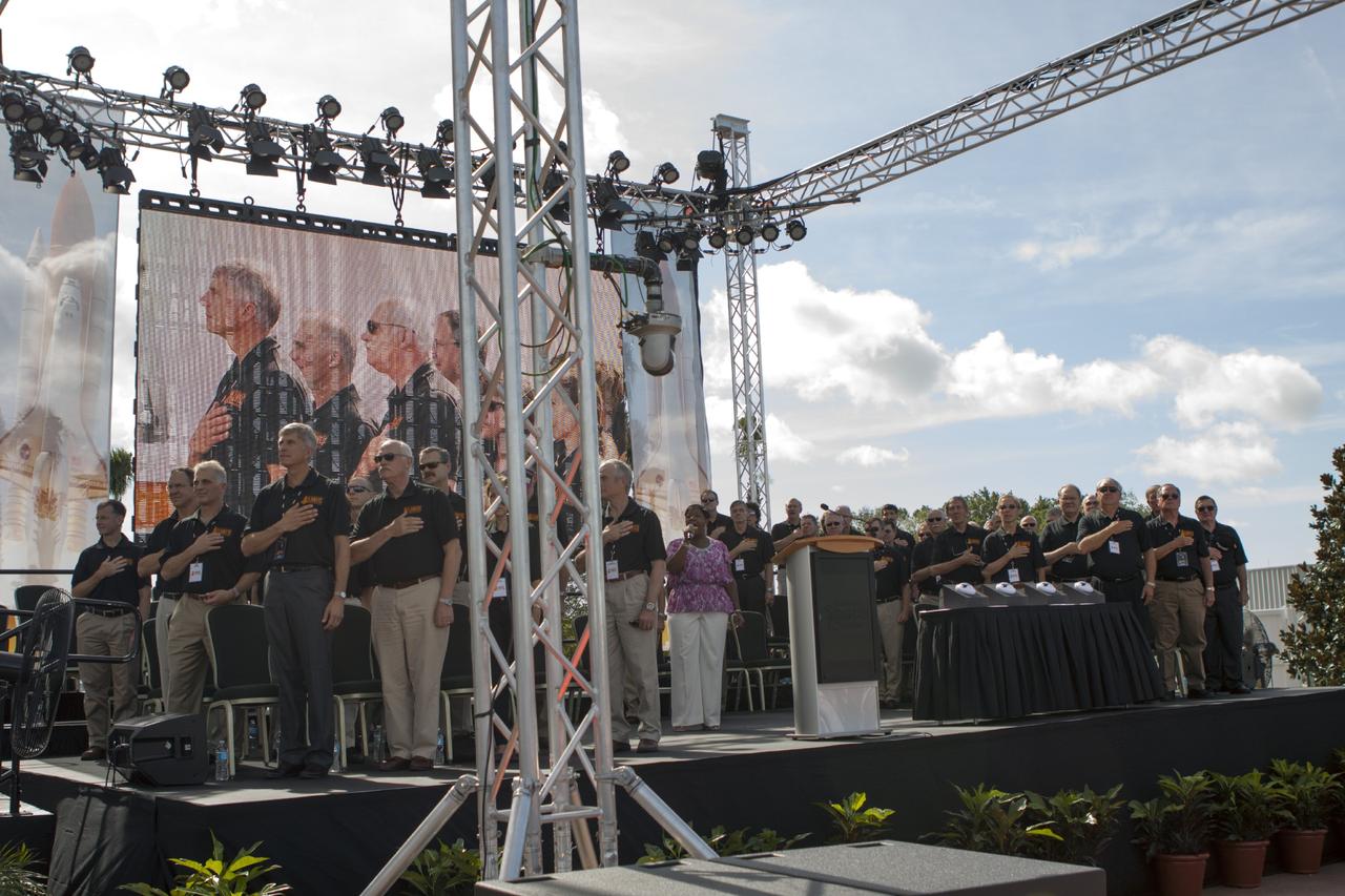CAPE CANAVERAL, Fla. -- At the Kennedy Space Center Visitor Complex in Florida, more than 40 space shuttle astronauts listen to the singing of the national anthem during opening ceremonies for the new 90,000-square-foot "Space Shuttle Atlantis" facility.      The new $100 million facility includes interactive exhibits that tell the story of the 30-year Space Shuttle Program and highlight the future of space exploration. The "Space Shuttle Atlantis" exhibit formally opened to the public on June 29, 2013.Photo credit: NASA/Jim Grossmann