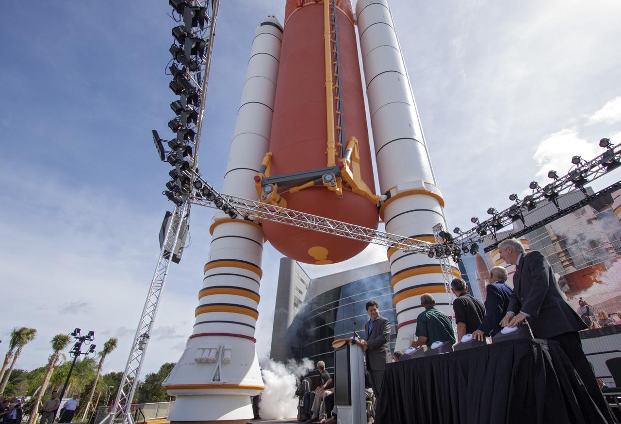 CAPE CANAVERAL, Fla. -- At the Kennedy Space Center Visitor Complex in Florida, CNN correspondent John Zarrella counted down for the ceremonial opening of the new "Space Shuttle Atlantis" facility. Smoke bellows near a full-scale set of space shuttle twin solid rocket boosters and external fuel tank at the entrance to the exhibit building. Looking on after pressing buttons to mark the opening the new exhibit, are, from the left, Charlie Bolden, NASA administrator, Bob Cabana, Kennedy director, Rick Abramson, Delaware North Parks and Resorts president, and Bill Moore, Delaware North Parks and Resorts chief operating officer.       The new $100 million facility includes interactive exhibits that tell the story of the 30-year Space Shuttle Program and highlight the future of space exploration. The "Space Shuttle Atlantis" exhibit formally opened to the public on June 29, 2013.Photo credit: NASA/Jim Grossmann