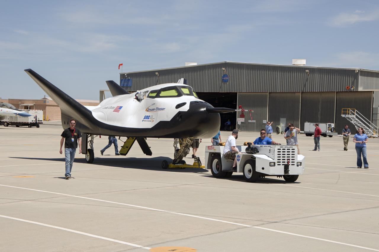 Edwards, Calif. – ED13-161-35 - Sierra Nevada Corporation SNC Space Systems' team members tow the Dream Chaser flight vehicle out to a concrete runway at NASA's Dryden Flight Research Center in California for range and taxi tow tests. The ground testing will validate the performance of the spacecraft's nose skid, brakes, tires and other systems prior to captive-carry and free-flight tests scheduled for later this year.    SNC is one of three companies working with NASA's Commercial Crew Program, or CCP, during the agency's Commercial Crew Integrated Capability, or CCiCap, initiative, which is intended to lead to the availability of commercial human spaceflight services for government and commercial customers. To learn more about CCP and its industry partners, visit www.nasa.gov/commercialcrew. Image credit: NASA/Ken Ulbrich