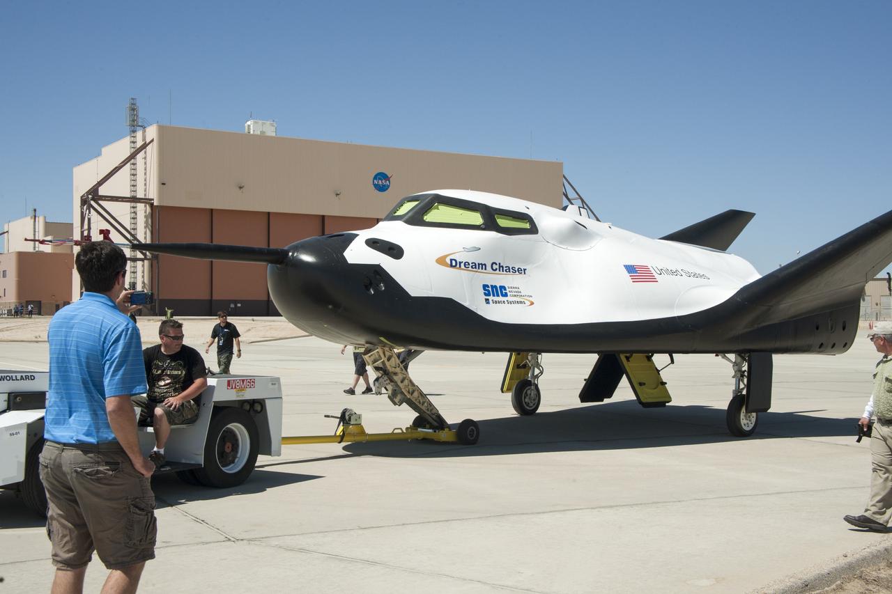 Edwards, Calif. – ED13-164-32 - Sierra Nevada Corporation SNC Space Systems' team members tow the Dream Chaser flight vehicle out to a concrete runway at NASA's Dryden Flight Research Center in California for range and taxi tow tests. The ground testing will validate the performance of the spacecraft's nose skid, brakes, tires and other systems prior to captive-carry and free-flight tests scheduled for later this year.      SNC is one of three companies working with NASA's Commercial Crew Program, or CCP, during the agency's Commercial Crew Integrated Capability, or CCiCap, initiative, which is intended to lead to the availability of commercial human spaceflight services for government and commercial customers. To learn more about CCP and its industry partners, visit www.nasa.gov/commercialcrew. Image credit: NASA/Ken Ulbrich