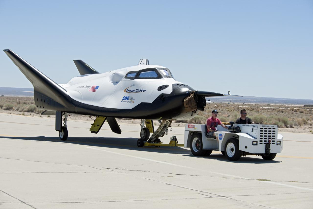 Edwards, Calif. – ED13-0215-072 - Sierra Nevada Corporation SNC Space Systems' team members tow the Dream Chaser flight vehicle along a concrete runway at NASA's Dryden Flight Research Center in California for range and taxi tow tests. The ground testing will validate the performance of the spacecraft's nose skid, brakes, tires and other systems prior to captive-carry and free-flight tests scheduled for later this year.  SNC is one of three companies working with NASA's Commercial Crew Program, or CCP, during the agency's Commercial Crew Integrated Capability, or CCiCap, initiative, which is intended to lead to the availability of commercial human spaceflight services for government and commercial customers. To learn more about CCP and its industry partners, visit www.nasa.gov/commercialcrew. Image credit: NASA/Ken Ulbrich