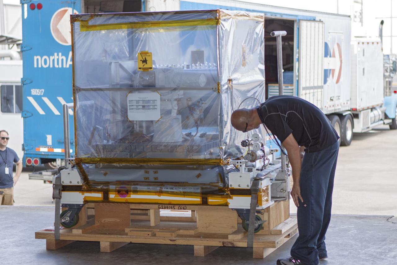 CAPE CANAVERAL, Fla. -- At NASA’s Kennedy Space Center in Florida, a technician monitors the progress as a forklift is used to move the Optical Payload for Lasercomm Science, or OPALS, experiment to the air lock entrance at the Space Station Processing Facility. The optical technology demonstration experiment arrived from the agency’s Jet Propulsion Laboratory in Pasadena, Calif.     NASA will use the International Space Station to test OPALS’ communications technology that could dramatically improve spacecraft communications, enhance commercial missions and strengthen transmission of scientific data. The experiment is slated to fly later this year aboard a SpaceX Dragon commercial resupply mission to the space station. The mission is expected to run 90 days after installation on the outside of the station. For more information about OPALS, visit: http://go.nasa.gov/10MMPDO. Photo credit: NASA/Jim Grossmann