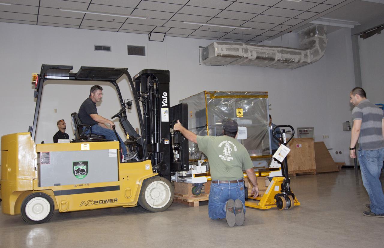 CAPE CANAVERAL, Fla. -- At NASA’s Kennedy Space Center in Florida, a technicians monitor the progress as a forklift is used to lower the Optical Payload for Lasercomm Science, or OPALS, experiment near the air lock entrance at the Space Station Processing Facility. The optical technology demonstration experiment arrived from the agency’s Jet Propulsion Laboratory in Pasadena, Calif.      NASA will use the International Space Station to test OPALS’ communications technology that could dramatically improve spacecraft communications, enhance commercial missions and strengthen transmission of scientific data. The experiment is slated to fly later this year aboard a SpaceX Dragon commercial resupply mission to the space station. The mission is expected to run 90 days after installation on the outside of the station. For more information about OPALS, visit: http://go.nasa.gov/10MMPDO. Photo credit: NASA/Jim Grossmann