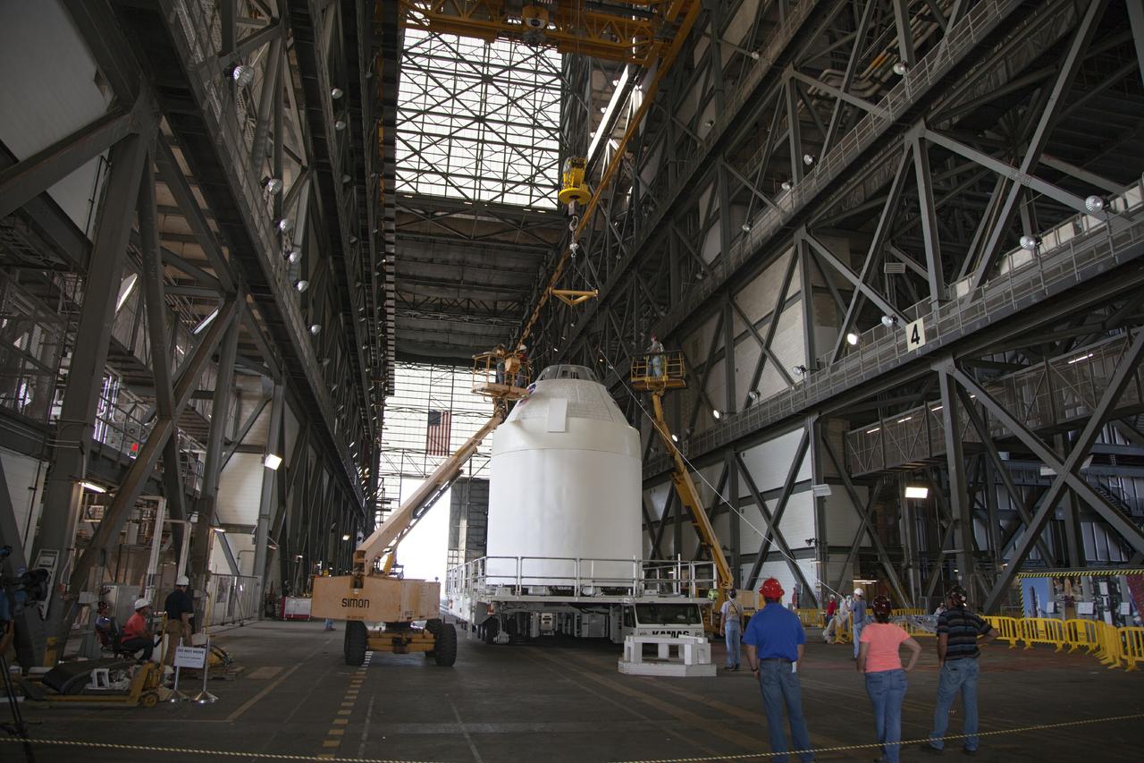 CAPE CANAVERAL, Fla. -- In the transfer aisle of the Vehicle Assembly Building at NASA’s Kennedy Space Center in Florida, a full-size mockup of the Orion spacecraft is being prepared for lifting into High Bay 4. Crane operators and technicians practice stacking and de-stacking operations in order to keep processing procedures and skills current for the Ground Systems Development and Operations Program.      Orion is the exploration spacecraft designed to carry crews to space beyond low Earth orbit. It will provide emergency abort capability, sustain the crew during the space travel and provide safe re-entry from deep space return velocities. Orion’s first unpiloted test flight is scheduled to launch in 2014 atop a Delta IV rocket. A second uncrewed flight test is scheduled for 2017 on NASA’s Space Launch System rocket. For more information, visit http://www.nasa.gov/orion. Photo credit: NASA/Dan Casper