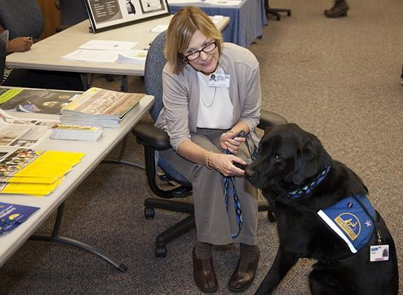 CAPE CANAVERAL, Fla. – Karen Herrsing, of Canine Companions for Independence, educates Kennedy Space Center workers on how Canine Companions for Independence can enhance the lives of others along with her furry friend, Dart, during the National Employee Health and Fitness Day event in the Operations and Checkout Building's Mission Briefing Room. Photo credit: NASA/Daniel Casper