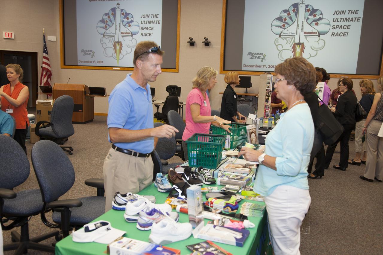 CAPE CANAVERAL, Fla. – Mark Hiebert, of the Running Zone, talks to a Kennedy worker during the National Employee Health and Fitness Day event in the Operations and Checkout Building's Mission Briefing Room. Employees also had the opportunity to be tested for diabetes, enter a raffle for prizes and get a five-minute massage. Other venders shown in the background are Sunseed Co-op’s Marcia Cooney, center, and Bridget Griffin from the YMCA of Titusville. Photo credit: NASA/Daniel Casper