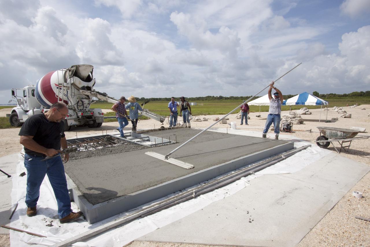 CAPE CANAVERAL, Fla. – At NASA’s Kennedy Space Center in Florida, technicians smooth out the concrete on the movable launch platform for the Project Morpheus lander at the north end of the Shuttle Landing Facility, or SLF. Testing of the prototype lander has been ongoing at NASA’s Johnson Space Center in Houston in preparation for free flight. The SLF will provide the lander with the kind of field necessary for realistic testing, complete with rocks, craters and hazards to avoid. Morpheus utilizes an autonomous landing and hazard avoidance technology, or ALHAT, payload that will allow it to navigate to clear landing sites amidst rocks, craters and other hazards during its descent. Project Morpheus is one of 20 small projects comprising the Advanced Exploration Systems, or AES, program in NASA’s Human Exploration and Operations Mission Directorate. AES projects pioneer new approaches for rapidly developing prototype systems, demonstrating key capabilities and validating operational concepts for future human missions beyond Earth orbit. For more information on Project Morpheus, visit http://www.nasa.gov/centers/johnson/exploration/morpheus/index.html. Photo credit: NASA/Jim Grossmann