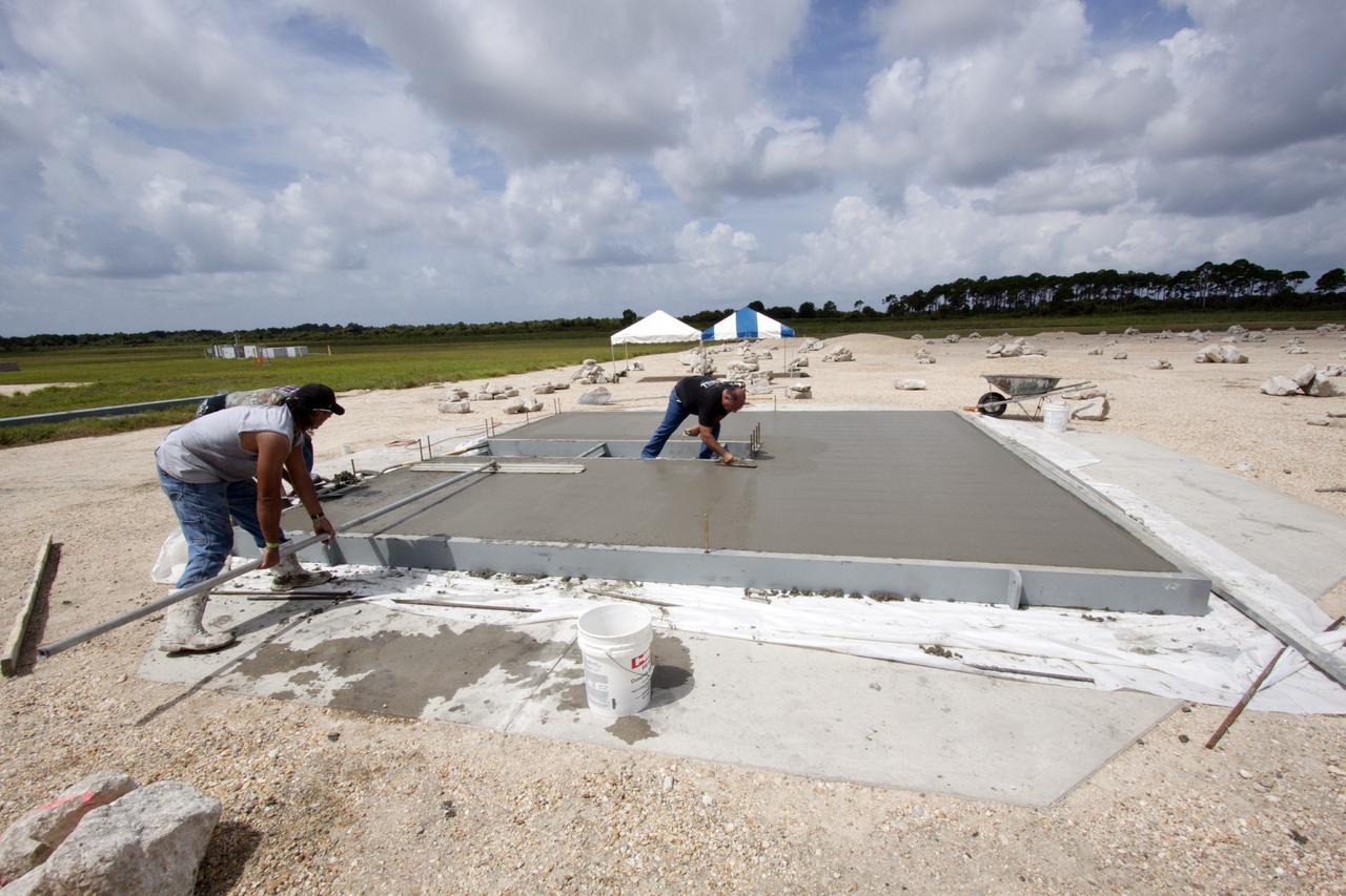 CAPE CANAVERAL, Fla. – At NASA’s Kennedy Space Center in Florida, technicians smooth out the concrete on the movable launch platform for the Project Morpheus lander at the north end of the Shuttle Landing Facility, or SLF. Testing of the prototype lander has been ongoing at NASA’s Johnson Space Center in Houston in preparation for free flight. The SLF will provide the lander with the kind of field necessary for realistic testing, complete with rocks, craters and hazards to avoid. Morpheus utilizes an autonomous landing and hazard avoidance technology, or ALHAT, payload that will allow it to navigate to clear landing sites amidst rocks, craters and other hazards during its descent. Project Morpheus is one of 20 small projects comprising the Advanced Exploration Systems, or AES, program in NASA’s Human Exploration and Operations Mission Directorate. AES projects pioneer new approaches for rapidly developing prototype systems, demonstrating key capabilities and validating operational concepts for future human missions beyond Earth orbit. For more information on Project Morpheus, visit http://www.nasa.gov/centers/johnson/exploration/morpheus/index.html. Photo credit: NASA/Jim Grossmann