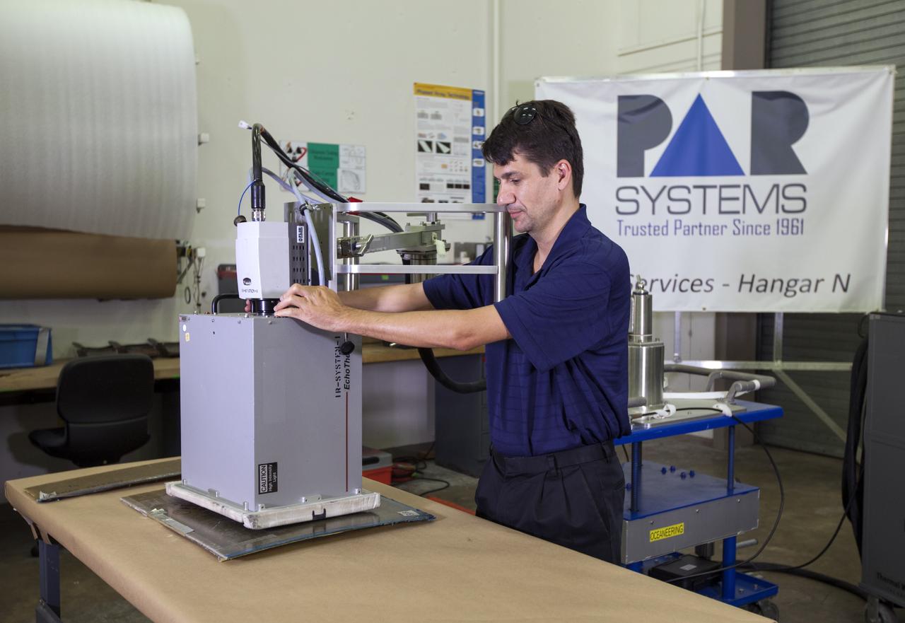 CAPE CANAVERAL, Fla. – In Hangar N at Cape Canaveral Air Force Station, PaR Systems, Inc. development engineer Bence Bertha sets up a flash thermography system. The equipment is used for inspecting hardware with thermal analysis.       NASA's Kennedy Space Center in Florida recently established a partnership agreement with PaR Systems, Inc. of Shoreview, Minn., for operation of the Hangar N facility and its nondestructive testing and evaluation equipment. As the spaceport transitions from a historically government-only launch facility to a multi-user spaceport for both federal and commercial customers, partnerships between the space agency and other organizations will be a key element in that effort. Hangar N is located at Cape Canaveral Air Force Station adjacent to Kennedy and houses a unique inventory of test and evaluation equipment and the capability for current and future mission spaceflight support. Photo credit: NASA/ Dimitri Gerondidakis