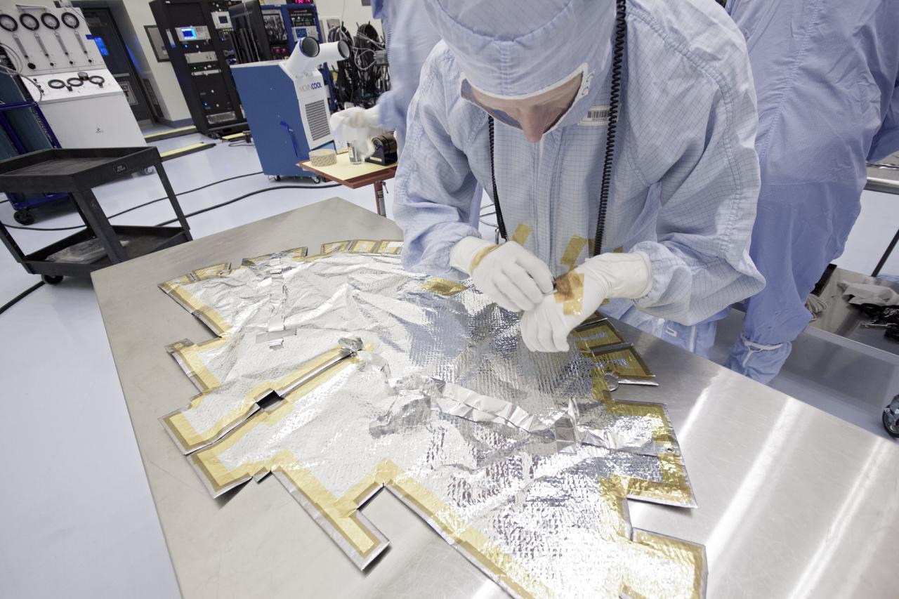 CAPE CANAVERAL, Fla. – Inside the Payload Hazardous Servicing Facility at NASA's Kennedy Space Center in Florida, technicians apply tape to the thermal blanket for the MAVEN spacecraft's parabolic high gain antenna. MAVEN stands for Mars Atmosphere and Volatile Evolution.      The antenna will communicate vast amounts of data to Earth during the mission. MAVEN is being prepared inside the facility for its scheduled November launch aboard a United Launch Alliance Atlas V rocket to Mars. Positioned in an orbit above the Red Planet, MAVEN will study the upper atmosphere of Mars in unprecedented detail. Photo credit: NASA/Jim Grossmann