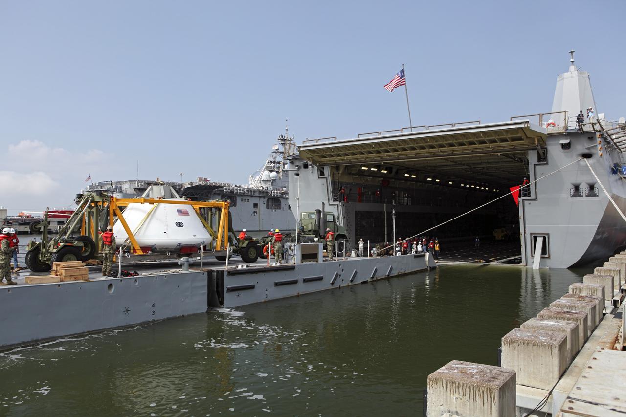 HAMPTON, Va. – At the Naval Station Norfolk near NASA’s Langley Research Center in Virginia, the Orion boilerplate test article and support equipment for a stationary recovery test are being transferred on a floating dock system to a U.S. Navy ship. NASA and the U.S. Navy are conducting tests to prepare for recovery of the Orion crew module and forward bay cover on its return from a deep space mission. The stationary recovery test will allow the teams to demonstrate and evaluate the recovery processes, procedures, hardware and personnel in a controlled environment before conducting a second recovery test next year in open waters. Orion is the exploration spacecraft designed to carry astronauts to destinations not yet explored by humans, including an asteroid and Mars. It will have emergency abort capability, sustain the crew during space travel and provide safe re-entry from deep space return velocities. The first unpiloted test flight of the Orion is scheduled to launch in 2014 atop a Delta IV rocket and in 2017 on NASA’s Space Launch System rocket. For more information, visit http://www.nasa.gov/orion. Photo credit: NASA/Dimitri Gerondidakis