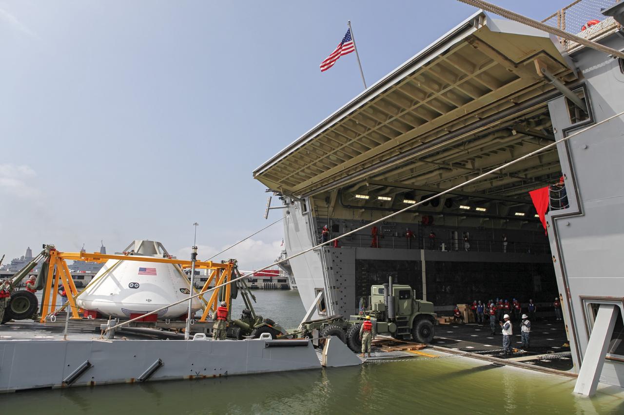 HAMPTON, Va. – At the Naval Station Norfolk near NASA’s Langley Research Center in Virginia, the Orion boilerplate test article and support equipment for a stationary recovery test are transferred by floating dock system to a U.S. Navy ship. NASA and the U.S. Navy are conducting tests to prepare for recovery of the Orion crew module and forward bay cover on its return from a deep space mission. The stationary recovery test will allow the teams to demonstrate and evaluate the recovery processes, procedures, hardware and personnel in a controlled environment before conducting a second recovery test next year in open waters. Orion is the exploration spacecraft designed to carry astronauts to destinations not yet explored by humans, including an asteroid and Mars. It will have emergency abort capability, sustain the crew during space travel and provide safe re-entry from deep space return velocities. The first unpiloted test flight of the Orion is scheduled to launch in 2014 atop a Delta IV rocket and in 2017 on NASA’s Space Launch System rocket. For more information, visit http://www.nasa.gov/orion. Photo credit: NASA/Dimitri Gerondidakis