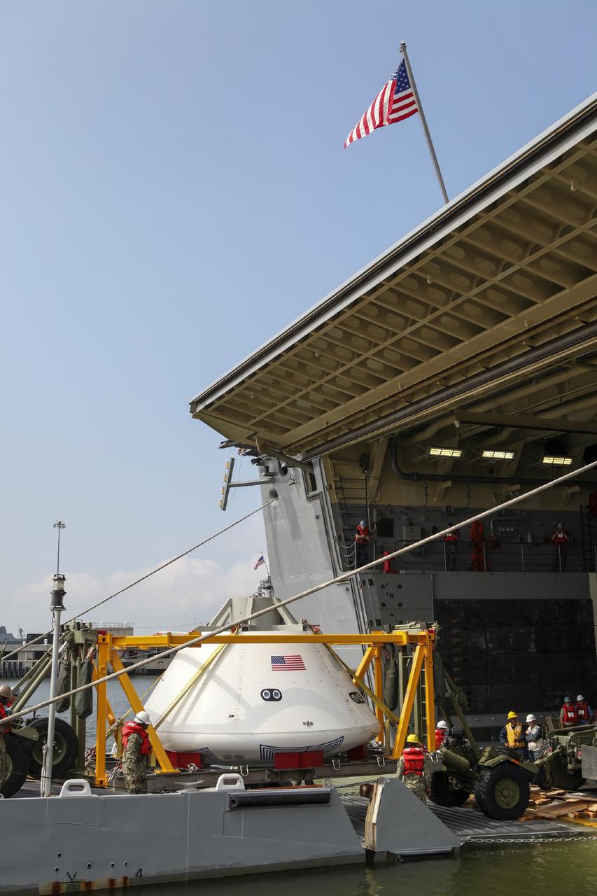 HAMPTON, Va. – At the Naval Station Norfolk near NASA’s Langley Research Center in Virginia, the Orion boilerplate test article and support equipment for a stationary recovery test are transferred by floating dock system to a U.S. Navy ship. NASA and the U.S. Navy are conducting tests to prepare for recovery of the Orion crew module and forward bay cover on its return from a deep space mission. The stationary recovery test will allow the teams to demonstrate and evaluate the recovery processes, procedures, hardware and personnel in a controlled environment before conducting a second recovery test next year in open waters. Orion is the exploration spacecraft designed to carry astronauts to destinations not yet explored by humans, including an asteroid and Mars. It will have emergency abort capability, sustain the crew during space travel and provide safe re-entry from deep space return velocities. The first unpiloted test flight of the Orion is scheduled to launch in 2014 atop a Delta IV rocket and in 2017 on NASA’s Space Launch System rocket. For more information, visit http://www.nasa.gov/orion. Photo credit: NASA/Dimitri Gerondidakis