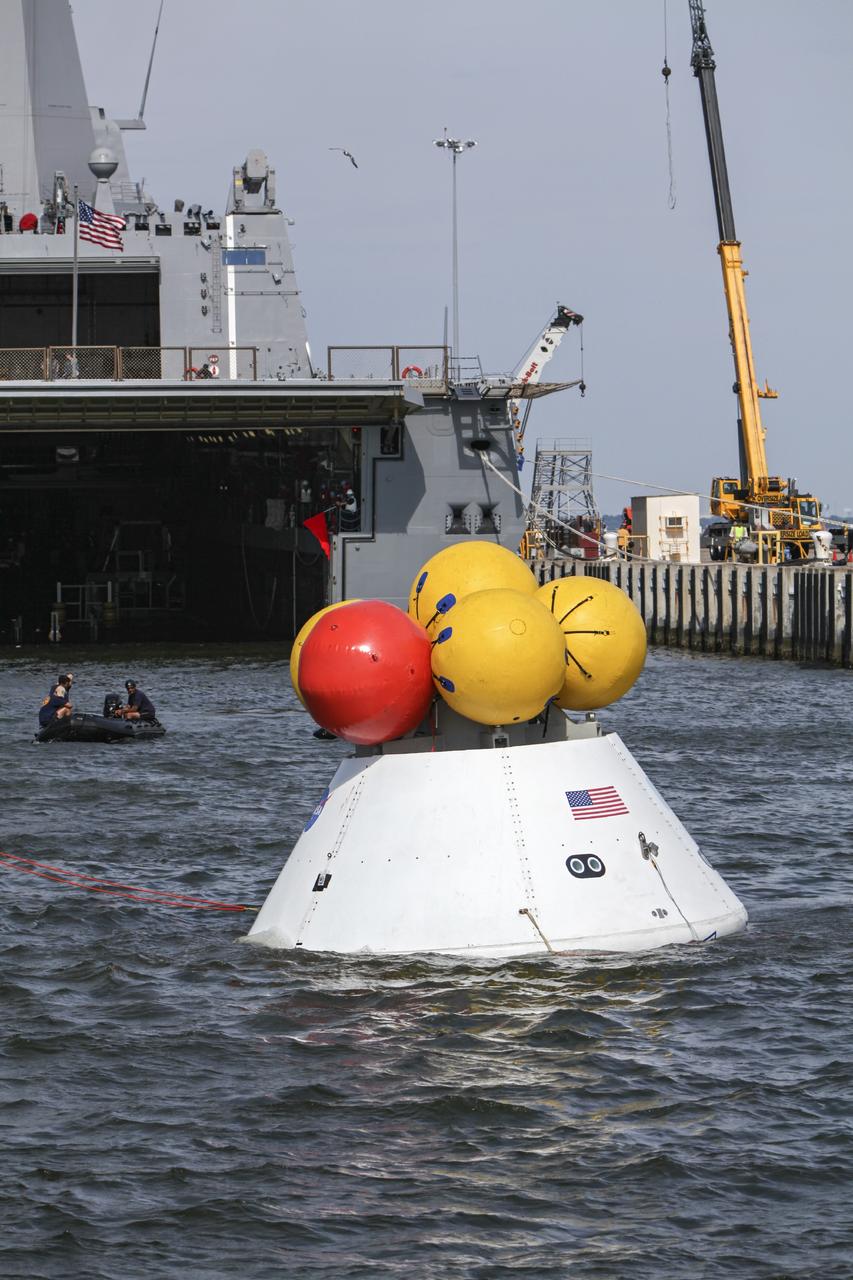 HAMPTON, Va. – At the Naval Station Norfolk near NASA’s Langley Research Center in Virginia, NASA and U.S. Navy personnel are conducting a stationary recovery test using the Orion boilerplate test article. The test article was transferred from a U.S. Navy ship into the water and tether lines have been attached. NASA and the U.S. Navy are conducting tests to prepare for recovery of the Orion crew module and forward bay cover on its return from a deep space mission. The stationary recovery test will allow the teams to demonstrate and evaluate the recovery processes, procedures, hardware and personnel in a controlled environment before conducting a second recovery test next year in open waters. Orion is the exploration spacecraft designed to carry astronauts to destinations not yet explored by humans, including an asteroid and Mars. It will have emergency abort capability, sustain the crew during space travel and provide safe re-entry from deep space return velocities. The first unpiloted test flight of the Orion is scheduled to launch in 2014 atop a Delta IV rocket and in 2017 on NASA’s Space Launch System rocket. For more information, visit http://www.nasa.gov/orion. Photo credit: NASA/Dimitri Gerondidakis