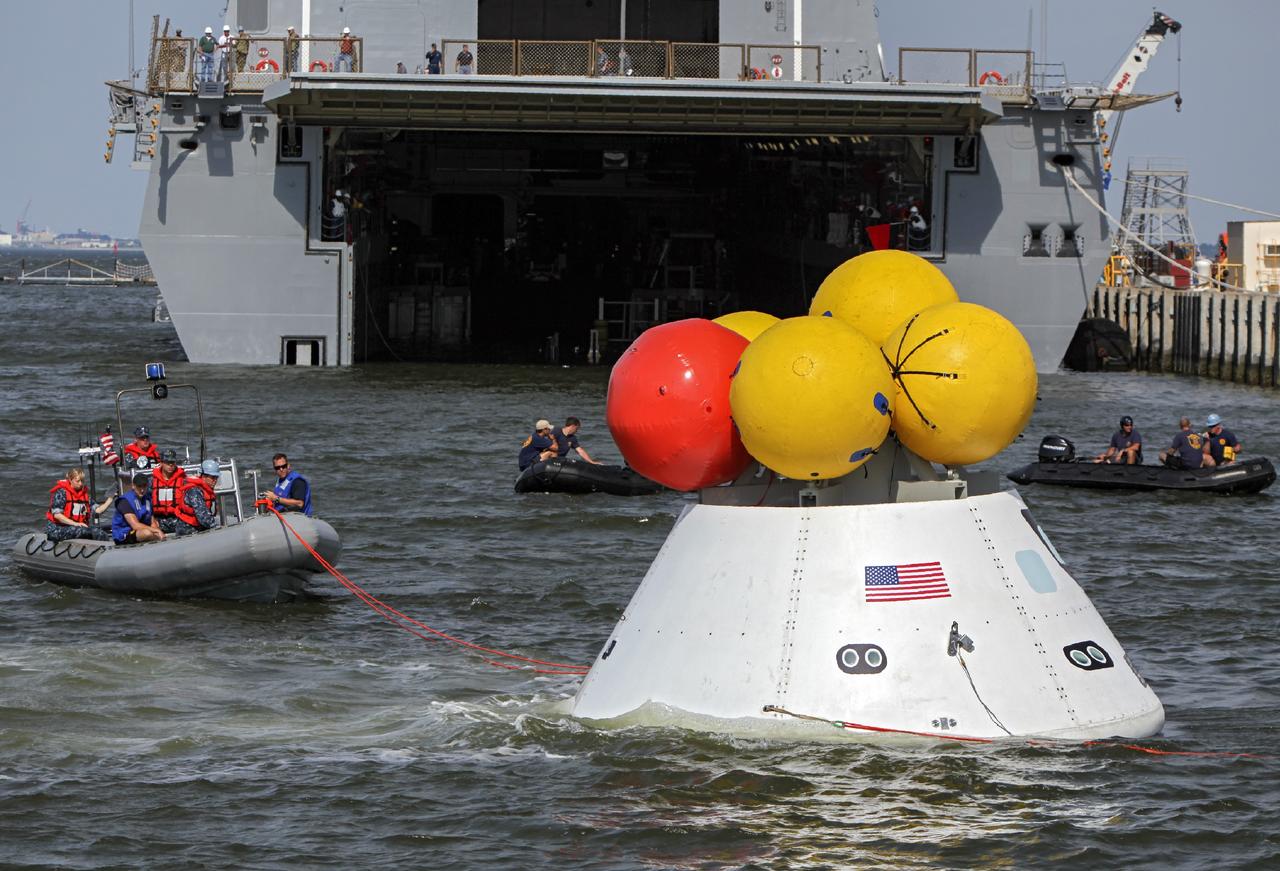 HAMPTON, Va. – At the Naval Station Norfolk near NASA’s Langley Research Center in Virginia, the Orion boilerplate test article floats in the water near a U.S. Navy ship during a stationary recovery test. NASA and the U.S. Navy are conducting tests to prepare for recovery of the Orion crew module and forward bay cover on its return from a deep space mission. The stationary recovery test will allow the teams to demonstrate and evaluate the recovery processes, procedures, hardware and personnel in a controlled environment before conducting a second recovery test next year in open waters. Orion is the exploration spacecraft designed to carry astronauts to destinations not yet explored by humans, including an asteroid and Mars. It will have emergency abort capability, sustain the crew during space travel and provide safe re-entry from deep space return velocities. The first unpiloted test flight of the Orion is scheduled to launch in 2014 atop a Delta IV rocket and in 2017 on NASA’s Space Launch System rocket. For more information, visit http://www.nasa.gov/orion. Photo credit: NASA/Dimitri Gerondidakis