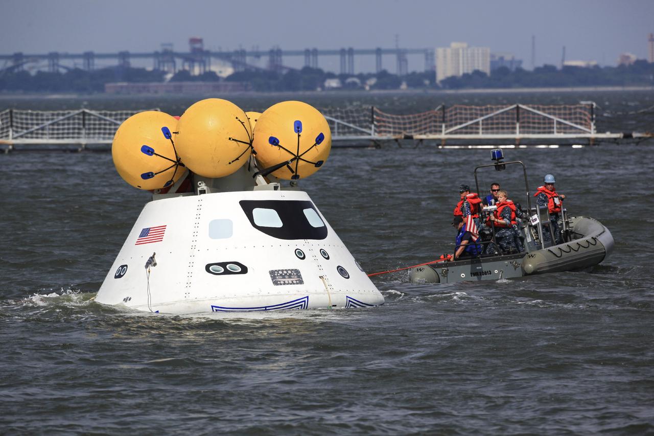HAMPTON, Va. – At the Naval Station Norfolk near NASA’s Langley Research Center in Virginia, U.S. Navy personnel approach the Orion boilerplate test article to remove a tether line during a stationary recovery test in the water. NASA and the U.S. Navy are conducting tests to prepare for recovery of the Orion crew module and forward bay cover on its return from a deep space mission. The stationary recovery test will allow the teams to demonstrate and evaluate the recovery processes, procedures, hardware and personnel in a controlled environment before conducting a second recovery test next year in open waters. Orion is the exploration spacecraft designed to carry astronauts to destinations not yet explored by humans, including an asteroid and Mars. It will have emergency abort capability, sustain the crew during space travel and provide safe re-entry from deep space return velocities. The first unpiloted test flight of the Orion is scheduled to launch in 2014 atop a Delta IV rocket and in 2017 on NASA’s Space Launch System rocket. For more information, visit http://www.nasa.gov/orion. Photo credit: NASA/Dimitri Gerondidakis