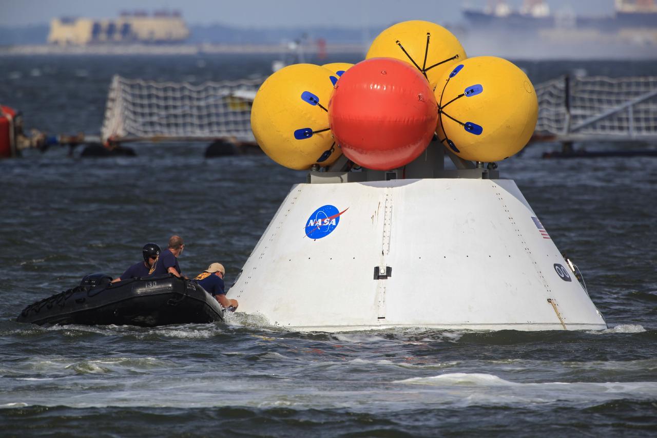 HAMPTON, Va. – At the Naval Station Norfolk near NASA’s Langley Research Center in Virginia, U.S. Navy personnel detach tether lines from the Orion boilerplate test article during a stationary recovery test in the water. NASA and the U.S. Navy are conducting tests to prepare for recovery of the Orion crew module and forward bay cover on its return from a deep space mission. The stationary recovery test will allow the teams to demonstrate and evaluate the recovery processes, procedures, hardware and personnel in a controlled environment before conducting a second recovery test next year in open waters. Orion is the exploration spacecraft designed to carry astronauts to destinations not yet explored by humans, including an asteroid and Mars. It will have emergency abort capability, sustain the crew during space travel and provide safe re-entry from deep space return velocities. The first unpiloted test flight of the Orion is scheduled to launch in 2014 atop a Delta IV rocket and in 2017 on NASA’s Space Launch System rocket. For more information, visit http://www.nasa.gov/orion. Photo credit: NASA/Dimitri Gerondidakis