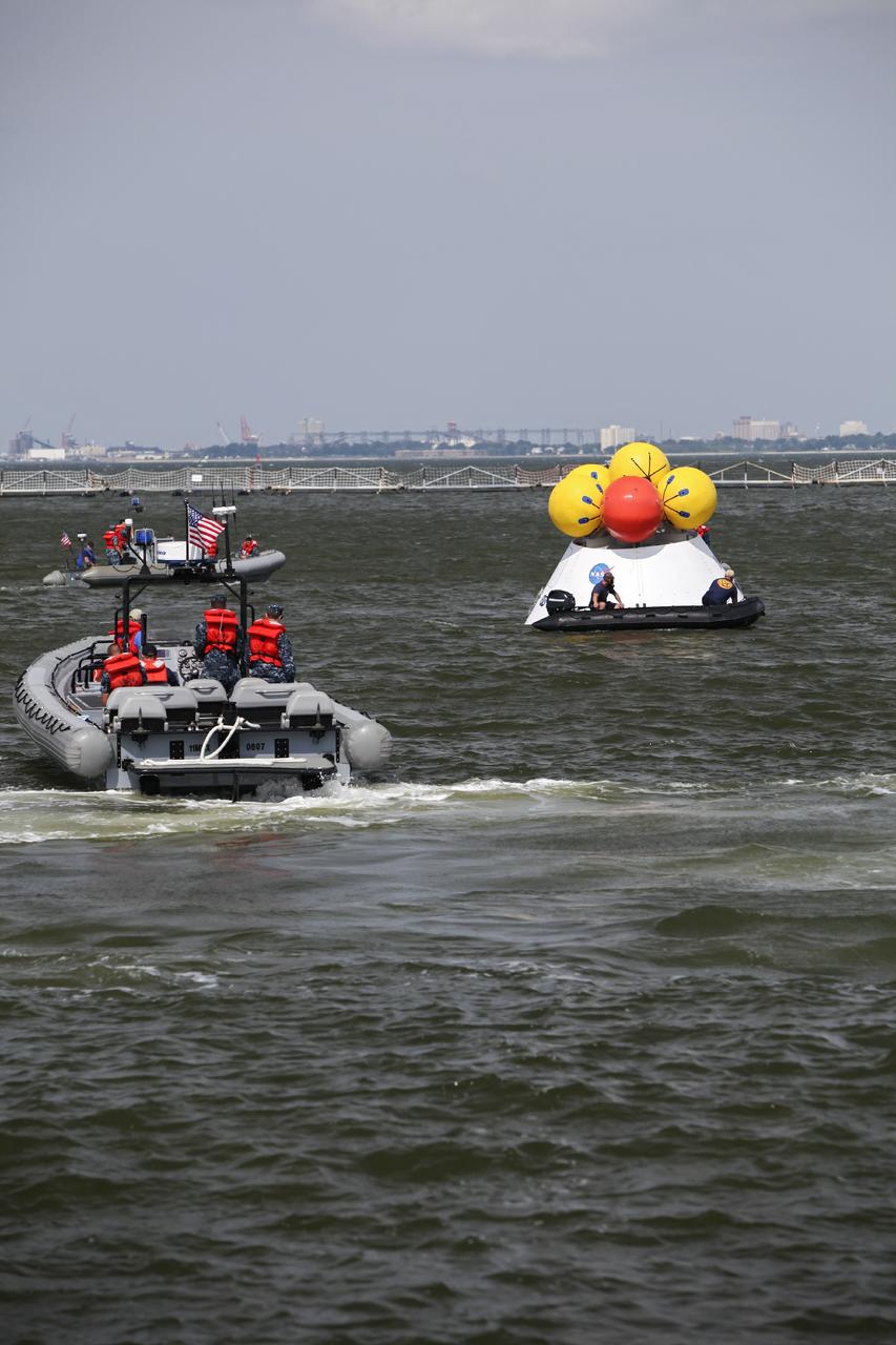 HAMPTON, Va. – At the Naval Station Norfolk near NASA’s Langley Research Center in Virginia, NASA and U.S. Navy personnel monitor the progress as the Orion boilerplate test article floats in the water during a stationary recovery test. NASA and the U.S. Navy are conducting tests to prepare for recovery of the Orion crew module and forward bay cover on its return from a deep space mission. The stationary recovery test will allow the teams to demonstrate and evaluate the recovery processes, procedures, hardware and personnel in a controlled environment before conducting a second recovery test next year in open waters. Orion is the exploration spacecraft designed to carry astronauts to destinations not yet explored by humans, including an asteroid and Mars. It will have emergency abort capability, sustain the crew during space travel and provide safe re-entry from deep space return velocities. The first unpiloted test flight of the Orion is scheduled to launch in 2014 atop a Delta IV rocket and in 2017 on NASA’s Space Launch System rocket. For more information, visit http://www.nasa.gov/orion. Photo credit: NASA/Dimitri Gerondidakis