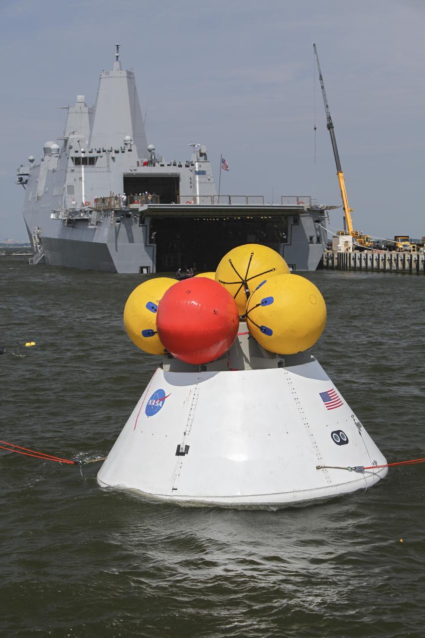 HAMPTON, Va. – At the Naval Station Norfolk near NASA’s Langley Research Center in Virginia, the Orion boilerplate test article floats in the water near a U.S. Navy ship during a stationary recovery test. NASA and the U.S. Navy are conducting tests to prepare for recovery of the Orion crew module and forward bay cover on its return from a deep space mission. The stationary recovery test will allow the teams to demonstrate and evaluate the recovery processes, procedures, hardware and personnel in a controlled environment before conducting a second recovery test next year in open waters. Orion is the exploration spacecraft designed to carry astronauts to destinations not yet explored by humans, including an asteroid and Mars. It will have emergency abort capability, sustain the crew during space travel and provide safe re-entry from deep space return velocities. The first unpiloted test flight of the Orion is scheduled to launch in 2014 atop a Delta IV rocket and in 2017 on NASA’s Space Launch System rocket. For more information, visit http://www.nasa.gov/orion. Photo credit: NASA/Dimitri Gerondidakis