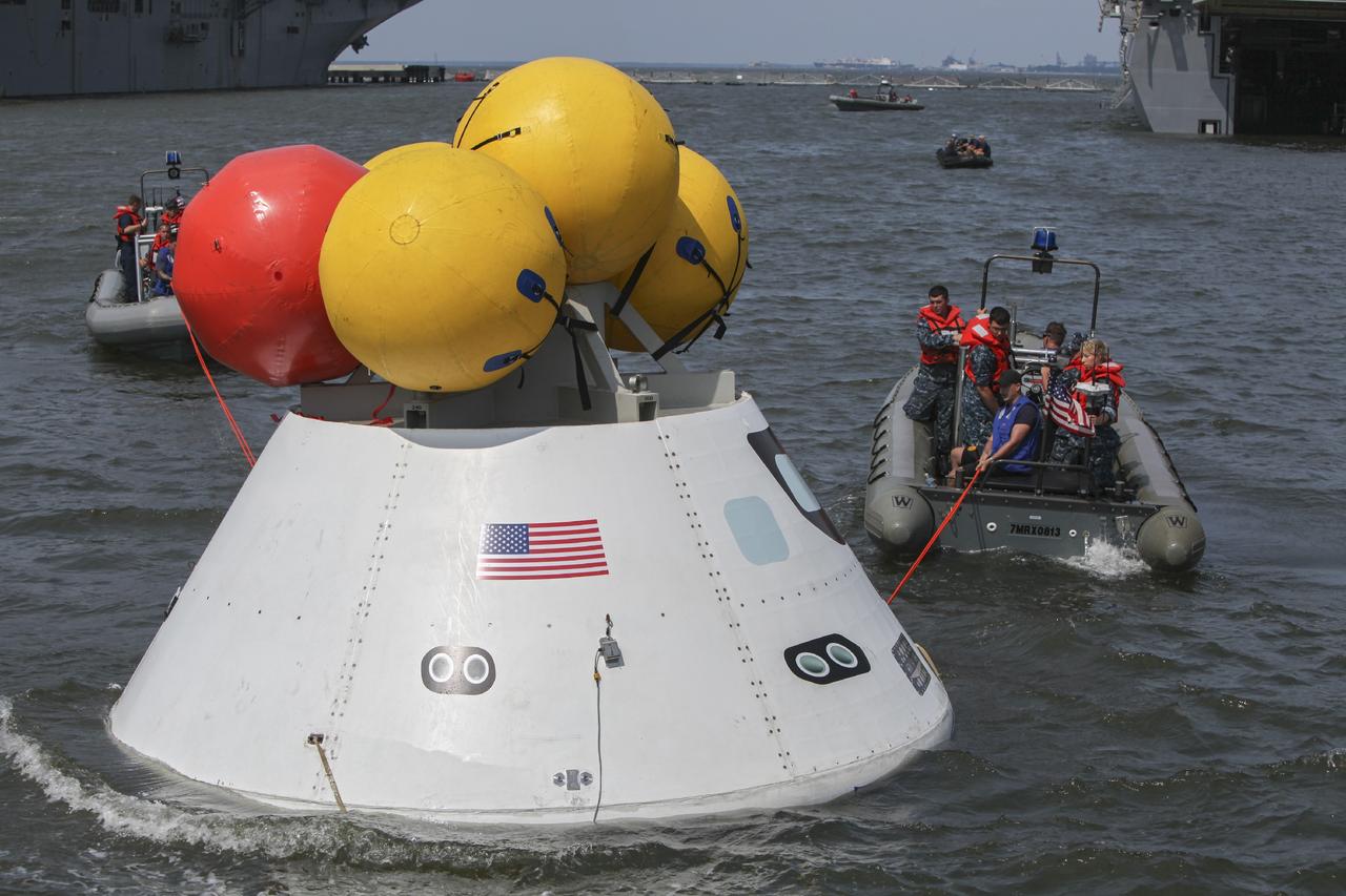 HAMPTON, Va. – At the Naval Station Norfolk near NASA’s Langley Research Center in Virginia, the Orion boilerplate test article floats in the water near a U.S. Navy ship during a stationary recovery test. NASA and the U.S. Navy are conducting tests to prepare for recovery of the Orion crew module and forward bay cover on its return from a deep space mission. The stationary recovery test will allow the teams to demonstrate and evaluate the recovery processes, procedures, hardware and personnel in a controlled environment before conducting a second recovery test next year in open waters. Orion is the exploration spacecraft designed to carry astronauts to destinations not yet explored by humans, including an asteroid and Mars. It will have emergency abort capability, sustain the crew during space travel and provide safe re-entry from deep space return velocities. The first unpiloted test flight of the Orion is scheduled to launch in 2014 atop a Delta IV rocket and in 2017 on NASA’s Space Launch System rocket. For more information, visit http://www.nasa.gov/orion. Photo credit: NASA/Dimitri Gerondidakis