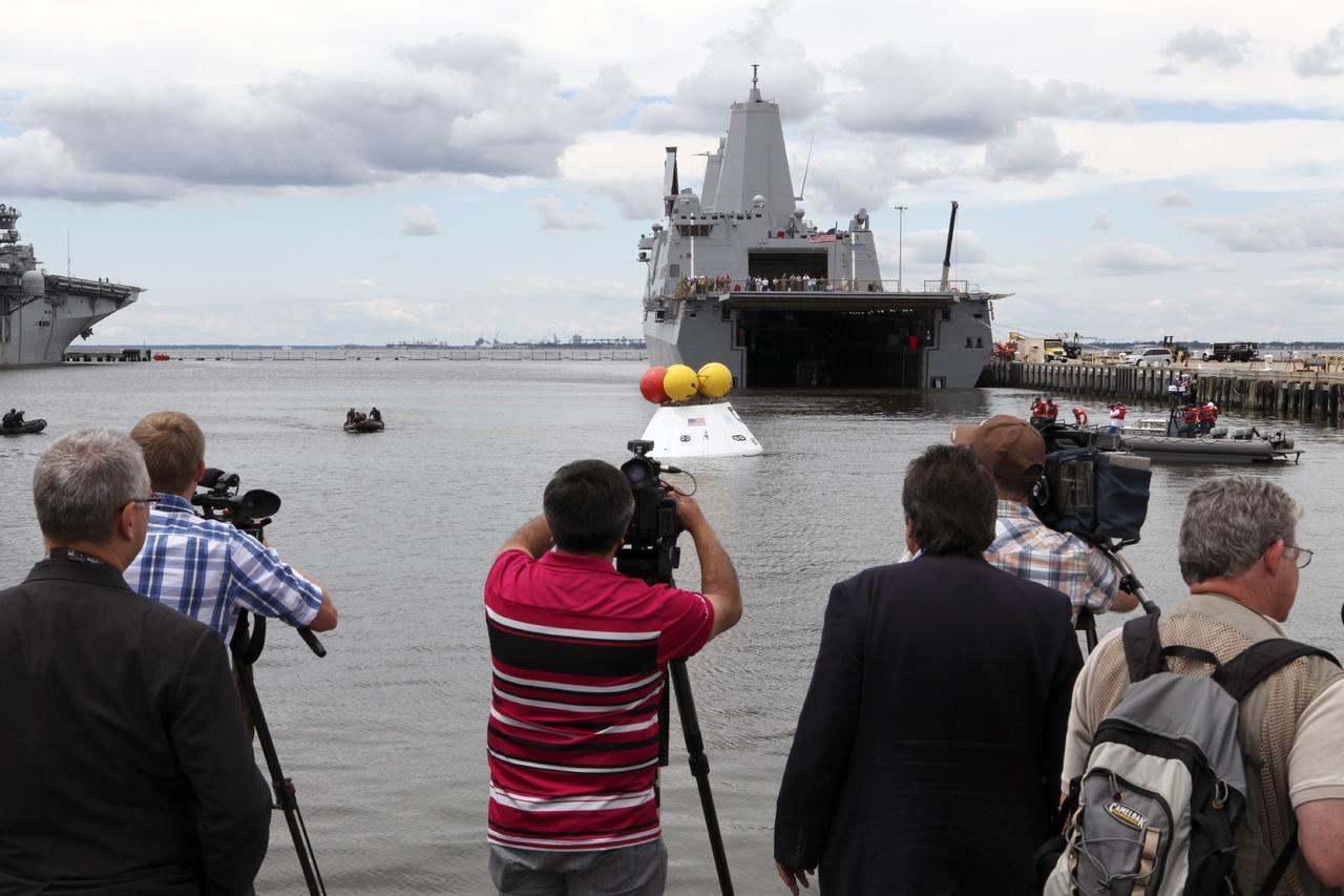 HAMPTON, Va. – At the Naval Station Norfolk near NASA’s Langley Research Center in Virginia, members of the news media observe the stationary recovery test being conducted on the Orion boilerplate test article in the water near a U.S. Navy ship. NASA and the U.S. Navy are conducting tests to prepare for recovery of the Orion crew module and forward bay cover on its return from a deep space mission. The stationary recovery test will allow the teams to demonstrate and evaluate the recovery processes, procedures, hardware and personnel in a controlled environment before conducting a second recovery test next year in open waters. Orion is the exploration spacecraft designed to carry astronauts to destinations not yet explored by humans, including an asteroid and Mars. It will have emergency abort capability, sustain the crew during space travel and provide safe re-entry from deep space return velocities. The first unpiloted test flight of the Orion is scheduled to launch in 2014 atop a Delta IV rocket and in 2017 on NASA’s Space Launch System rocket. For more information, visit http://www.nasa.gov/orion. Photo credit: NASA/Dimitri Gerondidakis