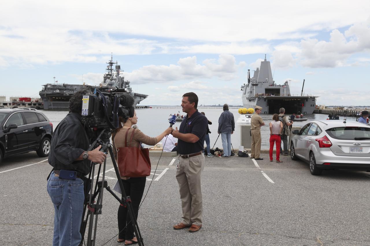 HAMPTON, Va. – At the Naval Station Norfolk near NASA’s Langley Research Center in Virginia, members of the news media speak with Louis Garcia, NASA recovery director, during the stationary recovery test being performed on the Orion boilerplate test in the water near a U.S. Navy ship. NASA and the U.S. Navy are conducting tests to prepare for recovery of the Orion crew module and forward bay cover on its return from a deep space mission. The stationary recovery test will allow the teams to demonstrate and evaluate the recovery processes, procedures, hardware and personnel in a controlled environment before conducting a second recovery test next year in open waters. Orion is the exploration spacecraft designed to carry astronauts to destinations not yet explored by humans, including an asteroid and Mars. It will have emergency abort capability, sustain the crew during space travel and provide safe re-entry from deep space return velocities. The first unpiloted test flight of the Orion is scheduled to launch in 2014 atop a Delta IV rocket and in 2017 on NASA’s Space Launch System rocket. For more information, visit http://www.nasa.gov/orion. Photo credit: NASA/Dimitri Gerondidakis