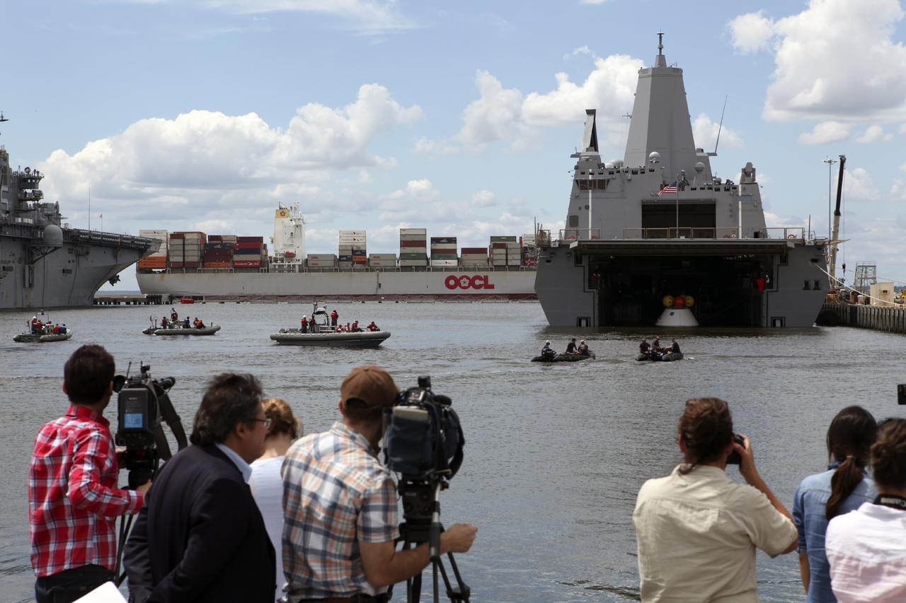 HAMPTON, Va. – At the Naval Station Norfolk near NASA’s Langley Research Center in Virginia, members of the news media observe the stationary recovery test being conducted on the Orion boilerplate test article in the water near a U.S. Navy ship. NASA and the U.S. Navy are conducting tests to prepare for recovery of the Orion crew module and forward bay cover on its return from a deep space mission. The stationary recovery test will allow the teams to demonstrate and evaluate the recovery processes, procedures, hardware and personnel in a controlled environment before conducting a second recovery test next year in open waters. Orion is the exploration spacecraft designed to carry astronauts to destinations not yet explored by humans, including an asteroid and Mars. It will have emergency abort capability, sustain the crew during space travel and provide safe re-entry from deep space return velocities. The first unpiloted test flight of the Orion is scheduled to launch in 2014 atop a Delta IV rocket and in 2017 on NASA’s Space Launch System rocket. For more information, visit http://www.nasa.gov/orion. Photo credit: NASA/Dimitri Gerondidakis