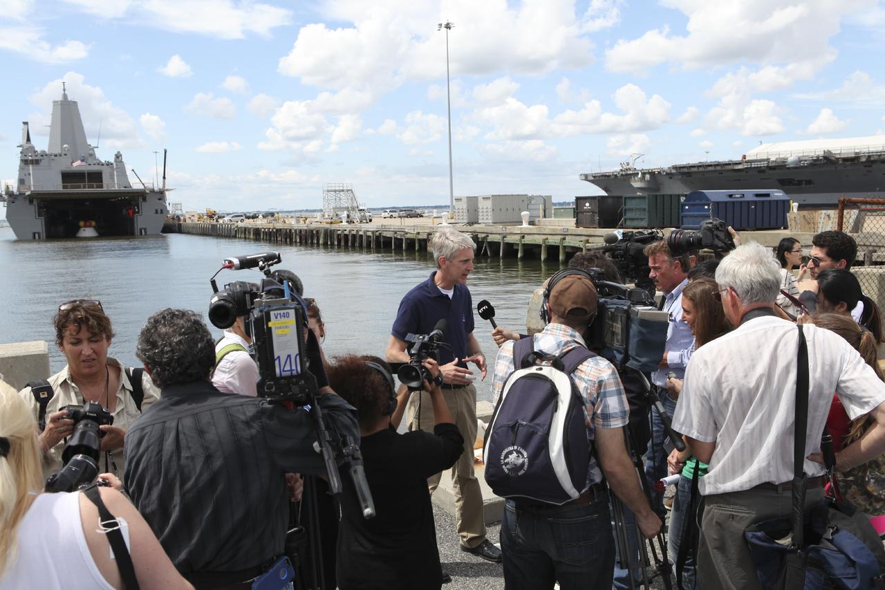 HAMPTON, Va. – At the Naval Station Norfolk near NASA’s Langley Research Center in Virginia, members of the news media speak with Scott Wilson, manager of Orion Production Operations at Kennedy Space Center in Florida, during the stationary recovery test being performed on the Orion boilerplate test in the water near a U.S. Navy ship. NASA and the U.S. Navy are conducting tests to prepare for recovery of the Orion crew module and forward bay cover on its return from a deep space mission. The stationary recovery test will allow the teams to demonstrate and evaluate the recovery processes, procedures, hardware and personnel in a controlled environment before conducting a second recovery test next year in open waters. Orion is the exploration spacecraft designed to carry astronauts to destinations not yet explored by humans, including an asteroid and Mars. It will have emergency abort capability, sustain the crew during space travel and provide safe re-entry from deep space return velocities. The first unpiloted test flight of the Orion is scheduled to launch in 2014 atop a Delta IV rocket and in 2017 on NASA’s Space Launch System rocket. For more information, visit http://www.nasa.gov/orion. Photo credit: NASA/Dimitri Gerondidakis