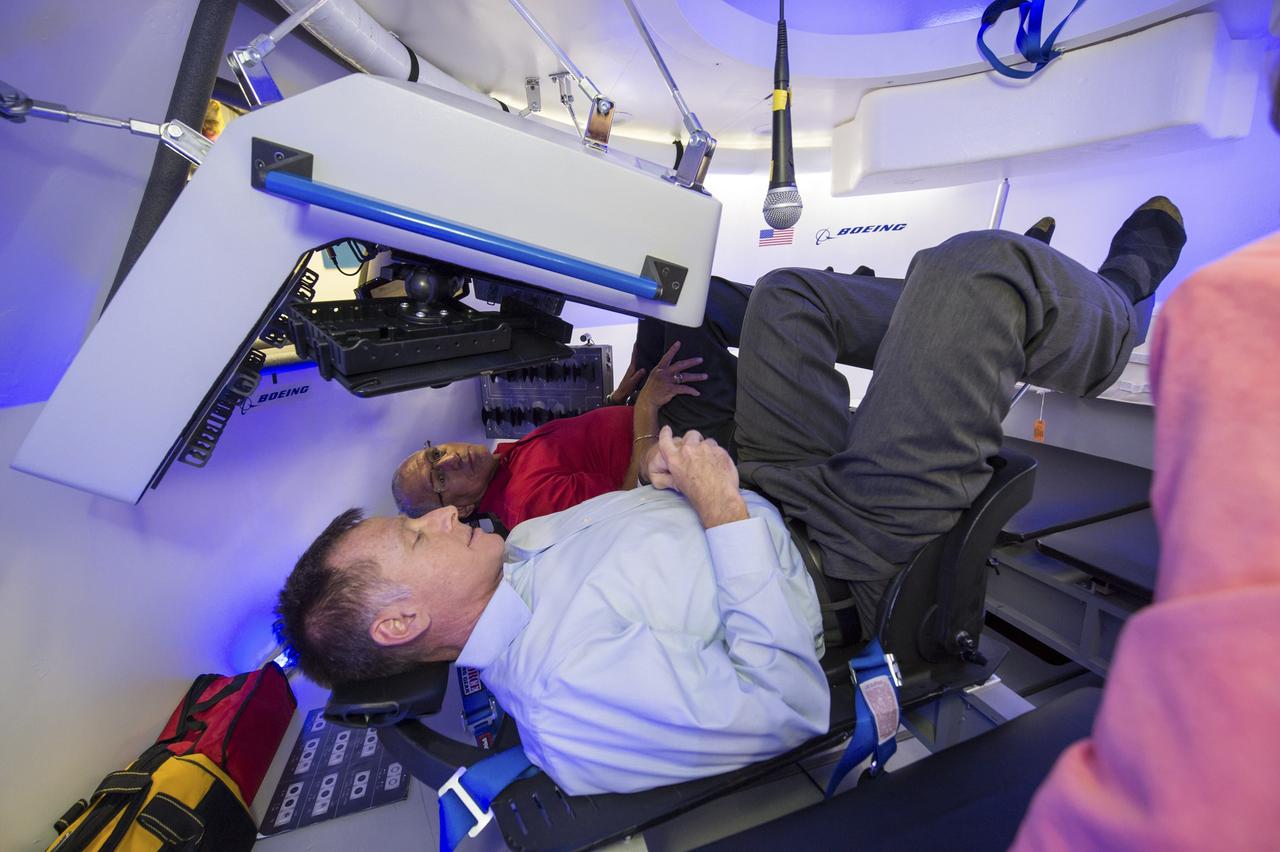 HOUSTON -- JSC-2013-E076055 -- The Boeing Company's Director of Crew and Mission Operations Chris Ferguson explains the control system of a mock-up CST-100 to NASA Administrator Charlie Bolden, back, at the company's Houston Product Support Center near Johnson Space Center. Boeing showcased its work on a fully outfitted test version of the spacecraft to Bolden and Johnson management. Boeing's CST-100 is designed to transport a mix of crew and cargo to low-Earth-orbit destinations. Boeing is one of three aerospace industry partners working with NASA's Commercial Crew Program, or CCP, during the Commercial Crew Integrated Capability, or CCiCap, initiative, which is intended to make commercial human spaceflight services available for government and commercial customers. To learn more about CCP, visit www.nasa.gov/commercialcrew. Photo credit: NASA/James Blair