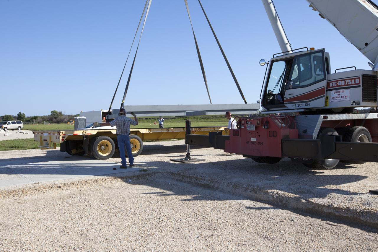 CAPE CANAVERAL, Fla. - At NASA’s Kennedy Space Center in Florida, workers enlist a crane to lift the movable launch platform for the Project Morpheus lander onto a flatbed truck for its move from the midfield to the north end of the Shuttle Landing Facility, or SLF. Testing of the prototype lander has been ongoing at NASA’s Johnson Space Center in Houston in preparation for free flight. The lander is scheduled for delivery to Kennedy in October. The SLF will provide the lander with the kind of field necessary for realistic testing, complete with rocks, craters and hazards to avoid. Morpheus utilizes an autonomous landing and hazard avoidance technology, or ALHAT, payload that will allow it to navigate to clear landing sites amidst obstacles during its descent. Project Morpheus is one of 20 small projects comprising the Advanced Exploration Systems, or AES, program in NASA’s Human Exploration and Operations Mission Directorate. AES projects pioneer new approaches for rapidly developing prototype systems, demonstrating key capabilities and validating operational concepts for future human missions beyond Earth orbit. For more information on Project Morpheus, visit http://www.nasa.gov/centers/johnson/exploration/morpheus/index.html. Photo credit: NASA/Kim Shiflett