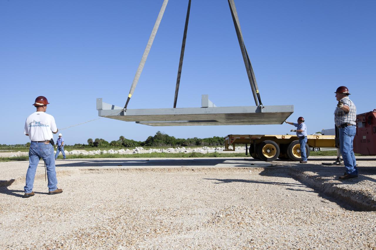 CAPE CANAVERAL, Fla. - At NASA’s Kennedy Space Center in Florida, workers enlist a crane to lift the movable launch platform for the Project Morpheus lander onto a flatbed truck for its move from the midfield to the north end of the Shuttle Landing Facility, or SLF. Testing of the prototype lander has been ongoing at NASA’s Johnson Space Center in Houston in preparation for free flight. The lander is scheduled for delivery to Kennedy in October. The SLF will provide the lander with the kind of field necessary for realistic testing, complete with rocks, craters and hazards to avoid. Morpheus utilizes an autonomous landing and hazard avoidance technology, or ALHAT, payload that will allow it to navigate to clear landing sites amidst obstacles during its descent. Project Morpheus is one of 20 small projects comprising the Advanced Exploration Systems, or AES, program in NASA’s Human Exploration and Operations Mission Directorate. AES projects pioneer new approaches for rapidly developing prototype systems, demonstrating key capabilities and validating operational concepts for future human missions beyond Earth orbit. For more information on Project Morpheus, visit http://www.nasa.gov/centers/johnson/exploration/morpheus/index.html. Photo credit: NASA/Kim Shiflett