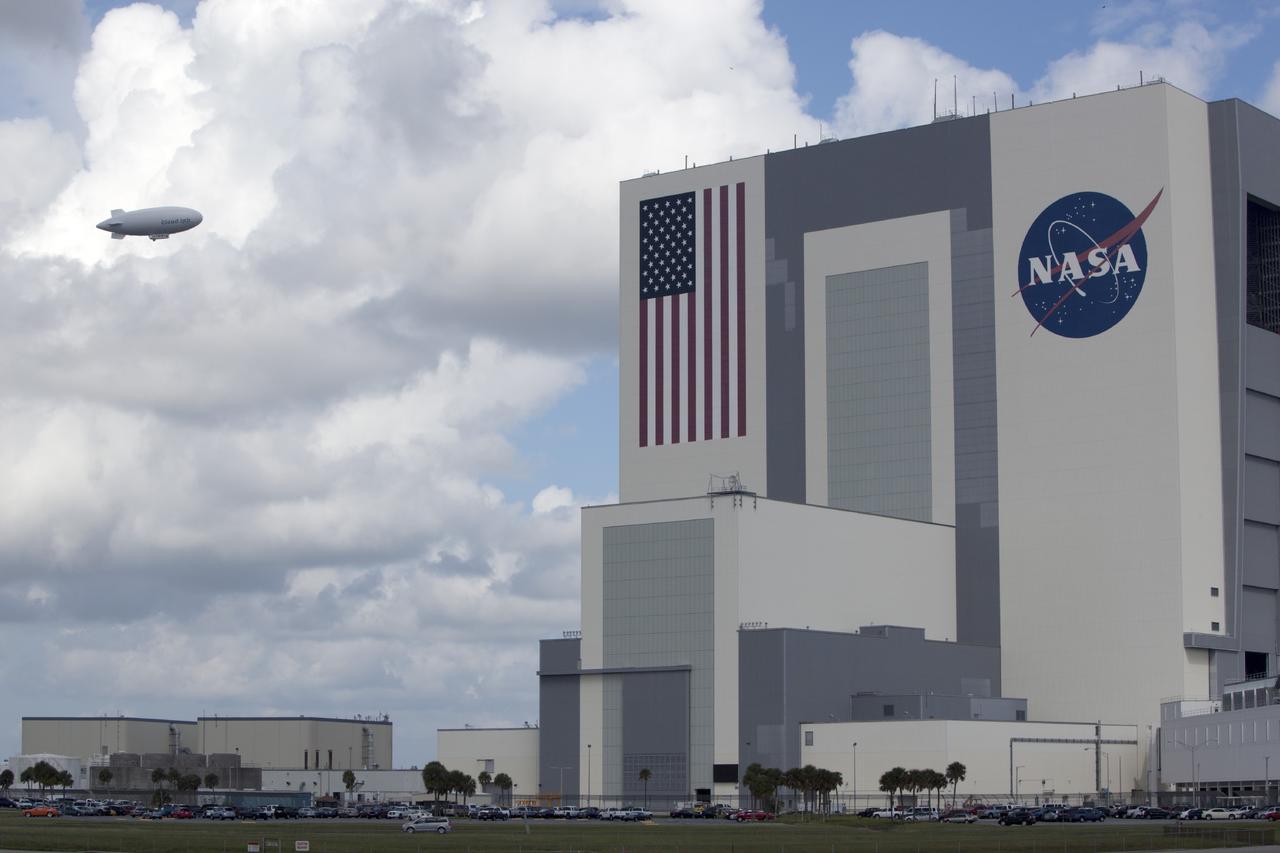CAPE CANAVERAL, Fla. -- An airship from the British Broadcasting Corp., or BBC, flies over the processing facilities in Launch Complex 39 toward the Vehicle Assembly Building at NASA's Kennedy Space Center in Florida. A team of scientists from the BBC's television project "Cloud Lab" are conducting a number of experiments aboard the airship as it flies across the U.S., exploring all aspects of the Earth's atmosphere. One of the experiments is NASA's Microorganisms in the Stratosphere, or MIST, which is designed to measure the microbial survival and cellular responses to exposure in the upper atmosphere. Photo credit: NASA/Dimitri Gerondidakis