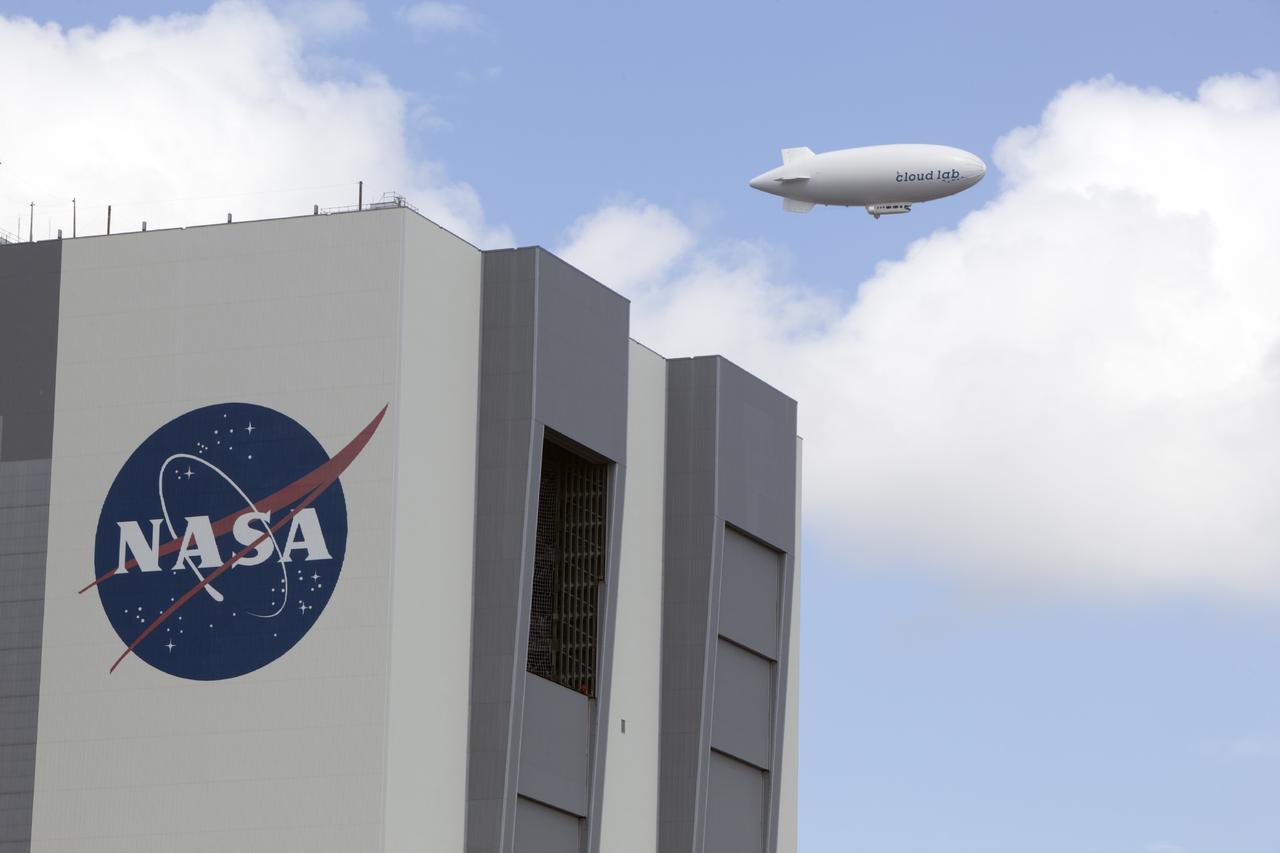 CAPE CANAVERAL, Fla. -- An airship from the British Broadcasting Corp., or BBC, flies over Launch Complex 39 past the Vehicle Assembly Building at NASA's Kennedy Space Center in Florida. A team of scientists from the BBC's television project "Cloud Lab" are conducting a number of experiments aboard the airship as it flies across the U.S., exploring all aspects of the Earth's atmosphere. One of the experiments is NASA's Microorganisms in the Stratosphere, or MIST, which is designed to measure the microbial survival and cellular responses to exposure in the upper atmosphere. Photo credit: NASA/Dimitri Gerondidakis