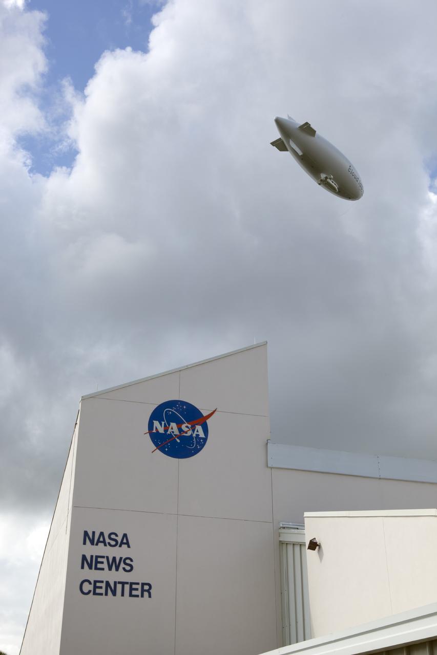 CAPE CANAVERAL, Fla. -- An airship from the British Broadcasting Corp., or BBC, flies over Launch Complex 39 past the NASA News Center at NASA's Kennedy Space Center in Florida.    A team of scientists from the BBC's television project "Cloud Lab" are conducting a number of experiments aboard the airship as it flies across the U.S., exploring all aspects of the Earth's atmosphere. One of the experiments is NASA's Microorganisms in the Stratosphere, or MIST, which is designed to measure the microbial survival and cellular responses to exposure in the upper atmosphere. Photo credit: NASA/Dimitri Gerondidakis