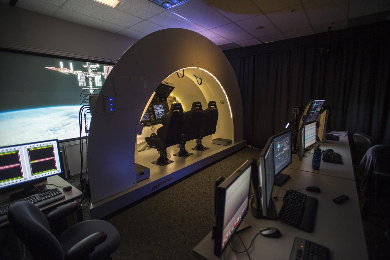 HOUSTON – A simulator of The Boeing Company's CST-100 spacecraft stands ready to begin evaluations of potential designs and software functions in a room at the company's Houston location. The CST-100 is under development in partnership between the company and NASA's Commercial Crew Program, or CCP. The spacecraft is designed to fly to low-Earth orbit and potentially dock with the International Space Station, which is seen on the screen in front of the simulator. Photo credit: The Boeing Company