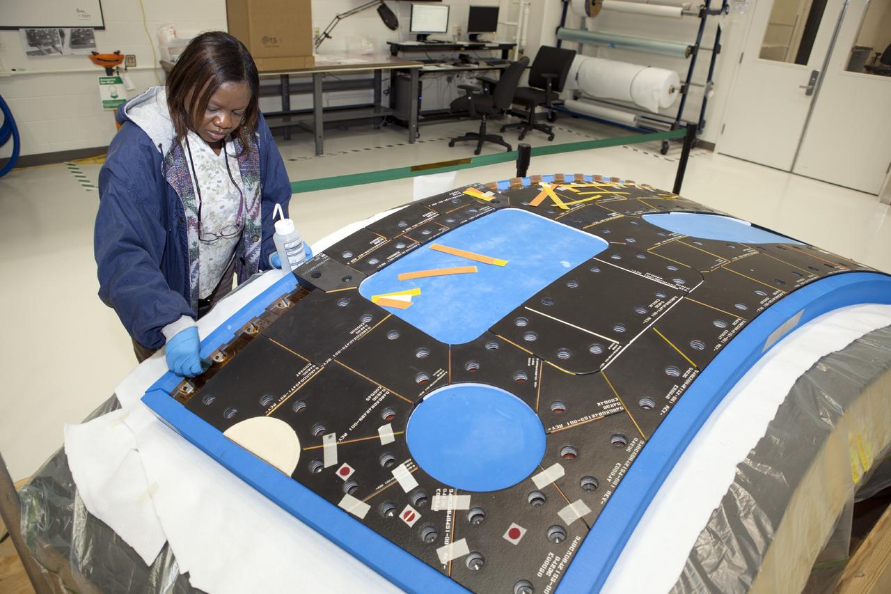 CAPE CANAVERAL, Fla. – Inside the Operations and Checkout Building high bay at NASA’s Kennedy Space Center in Florida, a tile technician works on a section of thermal protection system tiles that will be installed on the Orion crew module.    Orion is the exploration spacecraft designed to carry astronauts to destinations not yet explored by humans, including an asteroid and Mars. It will have emergency abort capability, sustain the crew during space travel and provide safe re-entry from deep space return velocities. The first unpiloted test flight of the Orion is scheduled to launch in 2014 atop a Delta IV rocket and in 2017 on NASA’s Space Launch System rocket. For more information, visit http://www.nasa.gov/orion. Photo credit: NASA/Dimitri Gerondidakis