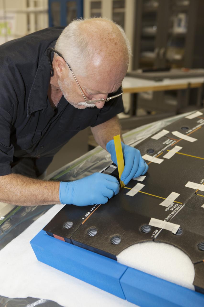 CAPE CANAVERAL, Fla. – Inside the Operations and Checkout Building high bay at NASA’s Kennedy Space Center in Florida, a tile technician places spacers between the thermal protection system tiles that will be installed on the Orion crew module.    Orion is the exploration spacecraft designed to carry astronauts to destinations not yet explored by humans, including an asteroid and Mars. It will have emergency abort capability, sustain the crew during space travel and provide safe re-entry from deep space return velocities. The first unpiloted test flight of the Orion is scheduled to launch in 2014 atop a Delta IV rocket and in 2017 on NASA’s Space Launch System rocket. For more information, visit http://www.nasa.gov/orion. Photo credit: NASA/Dimitri Gerondidakis