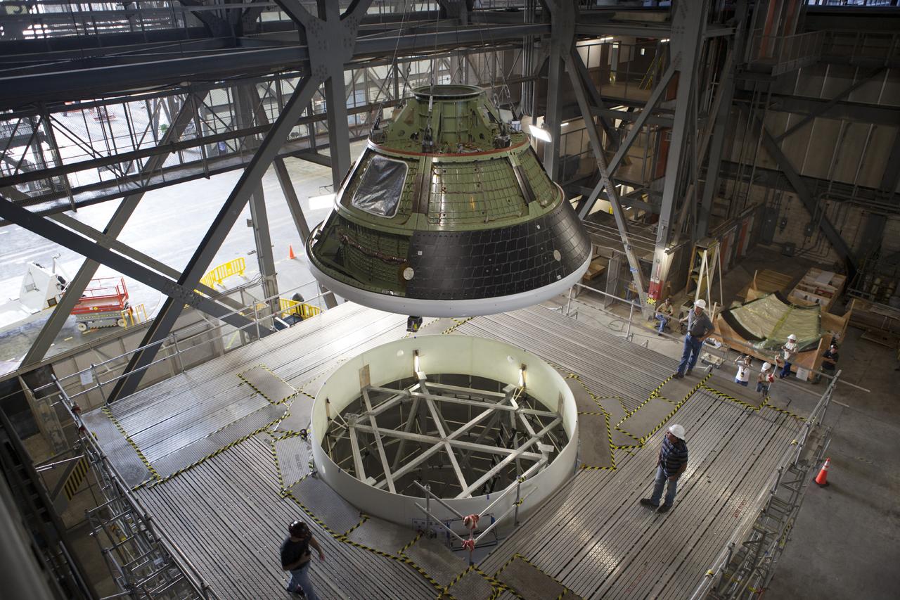 CAPE CANAVERAL, Fla. – At NASA’s Kennedy Space Center in Florida, technicians monitor the progress as the Orion ground test vehicle, or GTA, was lifted high in the air by crane in the transfer aisle of the Vehicle Assembly Building and is being lowered toward a mockup of the service module in high bay 4. The ground test vehicle is being used for path finding operations, including simulated manufacturing, assembly and stacking procedures. Orion is the exploration spacecraft designed to carry astronauts to destinations not yet explored by humans, including an asteroid and Mars. It will have emergency abort capability, sustain the crew during space travel and provide safe re-entry from deep space return velocities. The first unpiloted test flight of Orion is scheduled to launch in 2014 atop a Delta IV rocket and in 2017 on NASA’s Space Launch System rocket. For more information, visit www.nasa.gov/orion. Photo credit: Dimitri Gerondidakis
