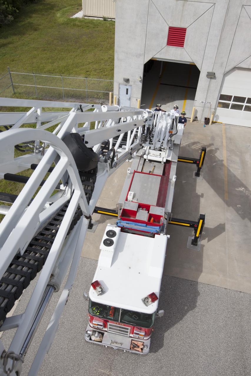 CAPE CANAVERAL, Fla. – At Fire Station No. 2 near the Shuttle Landing Facility at NASA’s Kennedy Space Center in Florida, a bird’s eye view reveals the ladder has been extended on the aerial fire truck during a training exercise. The stabilizers have been deployed on either side of the fire truck.    The center’s Fire Rescue Services recently achieved Pro Board Certification in aerial fire truck operations. Pro Board Certification is a globally recognized certification that puts on multiple courses that all fire departments throughout the world recognize and use to train their personnel. The unique aerial truck contains a 100-foot extendable ladder with a bucket at the end of it that can be used for rescues from taller buildings or aircraft rescue firefighting. Photo credit: NASA/Kim Shiflett