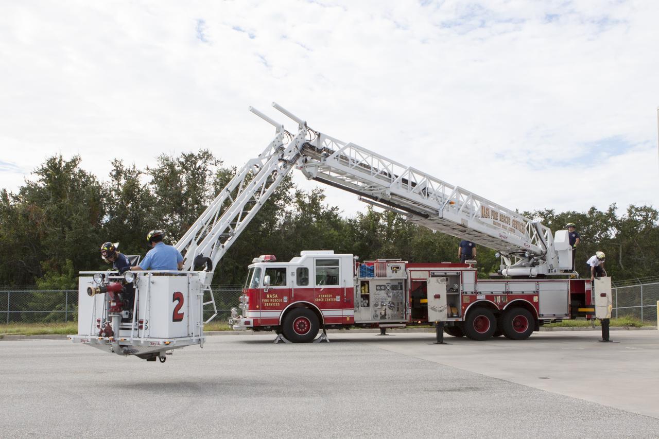 CAPE CANAVERAL, Fla. – At Fire Station No. 2 near the Shuttle Landing Facility at NASA’s Kennedy Space Center in Florida, Fire Rescue Services personnel lower the extendable ladder so that two fire rescue workers can exit the bucket during training to be certified in the operation and use of the vehicle.    The center’s Fire Rescue Services recently achieved Pro Board Certification in aerial fire truck operations. Pro Board Certification is a globally recognized certification that puts on multiple courses that all fire departments throughout the world recognize and use to train their personnel. The unique aerial truck contains a 100-foot extendable ladder with a bucket at the end of it that can be used for rescues from taller buildings or aircraft rescue firefighting. Photo credit: NASA/Kim Shiflett