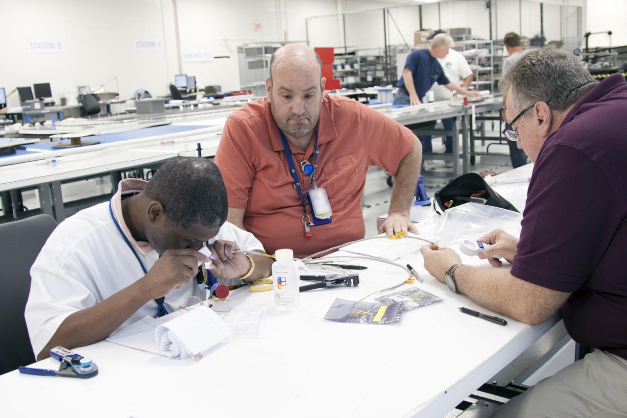 CAPE CANAVERAL, Fla. – Inside the Operations and Checkout Building high bay at NASA’s Kennedy Space Center in Florida, technicians look over components that will be installed on the service module bulkhead for the Orion spacecraft. Orion is the exploration spacecraft designed to carry astronauts to destinations not yet explored by humans, including an asteroid and Mars. It will have emergency abort capability, sustain the crew during space travel and provide safe re-entry from deep space return velocities. The first unpiloted test flight of the Orion is scheduled to launch in 2014 atop a Delta IV rocket and in 2017 on NASA’s Space Launch System rocket. For more information, visit http://www.nasa.gov/orion. Photo credit: NASA/Jim Grossmann