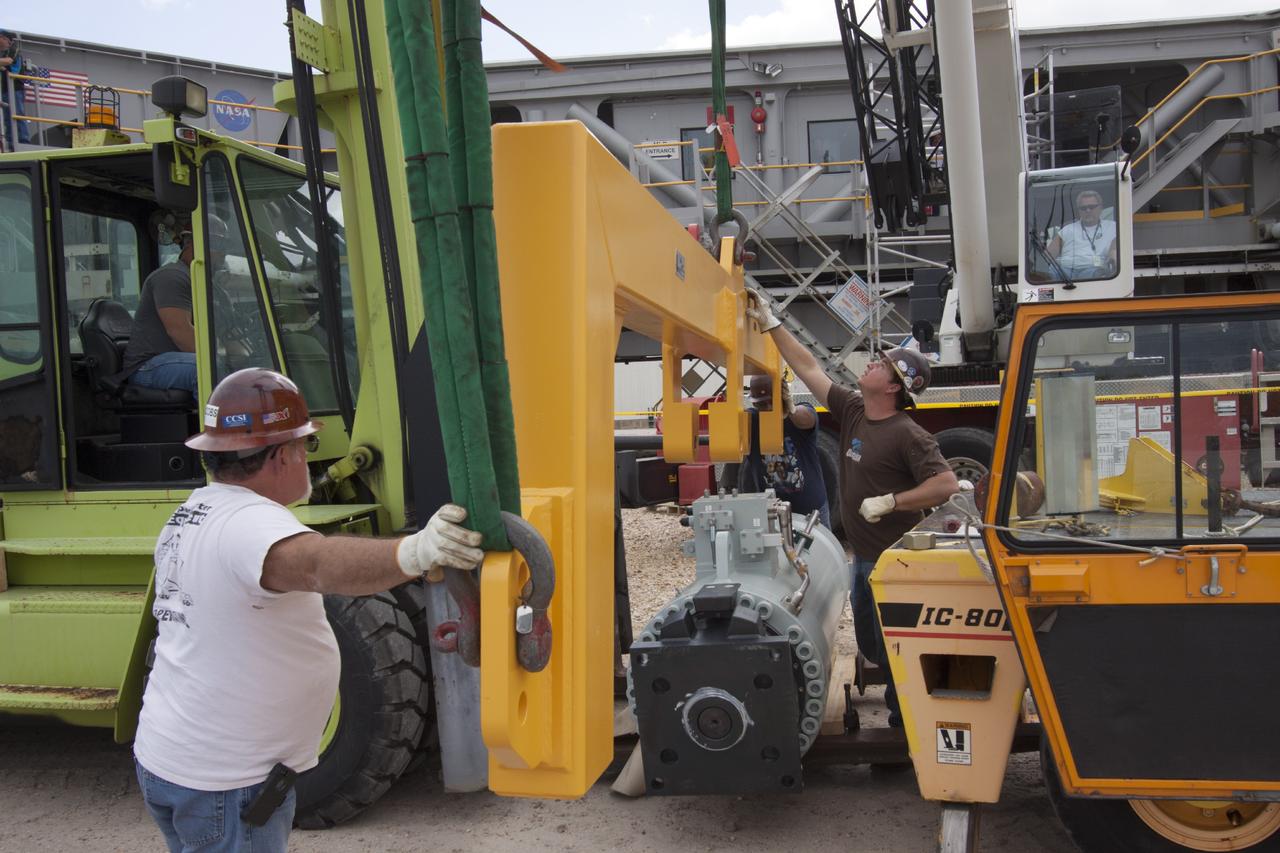 CAPE CANAVERAL, Fla. – Ground support equipment technicians monitor the progress as a forklift is used to carry a new jacking, equalizing and leveling, or JEL, hydraulic cylinder for installation on crawler-transporter 1 at the crawler transporter maintenance facility at NASA’s Kennedy Space Center in Florida. New JEL hydraulic cylinders will be installed on CT-1 to test them for increased load carrying capacity and reliability. The Ground Systems Development and Operations Program at Kennedy continues to upgrade CT-1 as part of its general maintenance. CT-1 could be available to carry a variety of launch vehicles to the launch pad. Two crawler-transporters were used to carry the mobile launcher platform and space shuttle to Launch Complex 39 for space shuttle launches for 30 years. Photo credit: NASA/Jim Grossmann