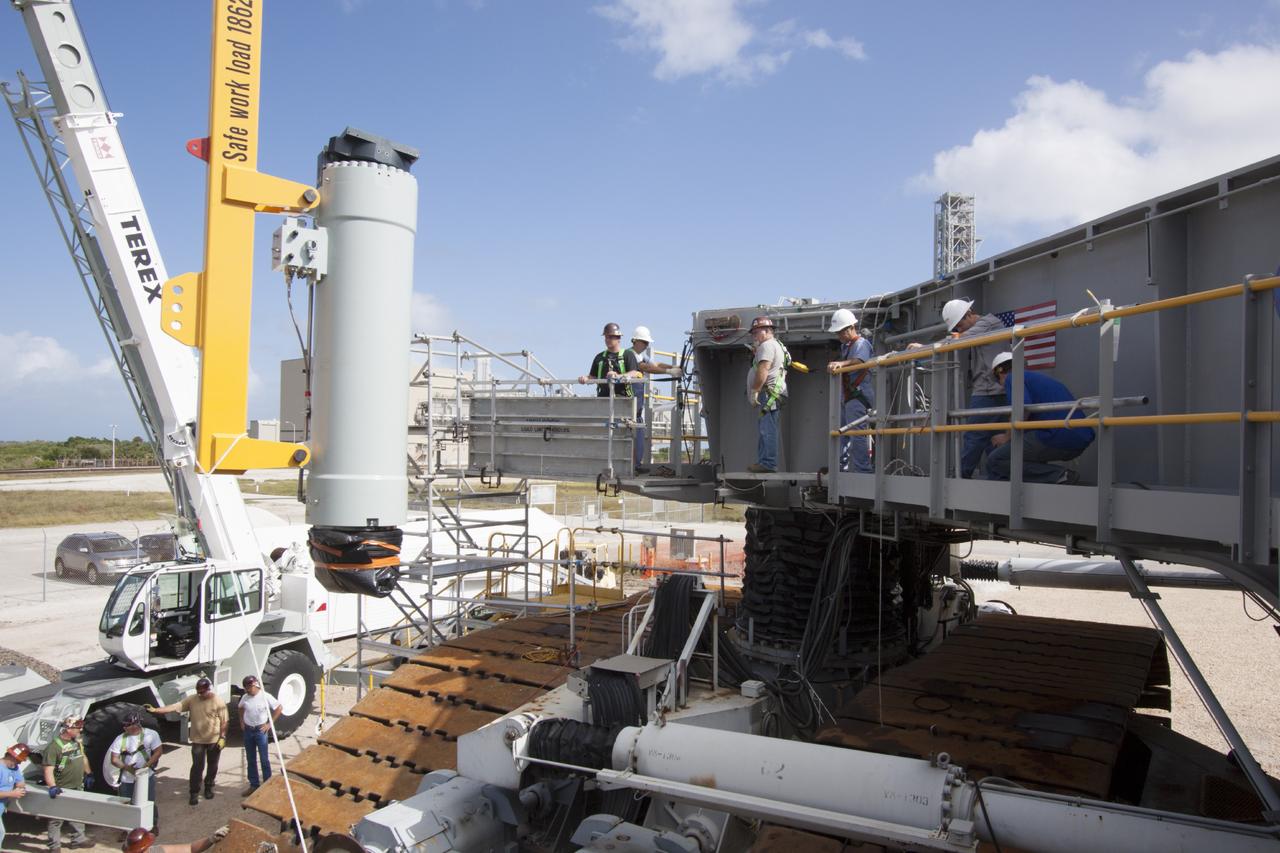 CAPE CANAVERAL, Fla. – Ground support equipment technicians monitor the progress as a crane is used to lift and move a new jacking, equalizing and leveling, or JEL, hydraulic cylinder for installation on crawler-transporter 1 at the crawler transporter maintenance facility at NASA’s Kennedy Space Center in Florida. New JEL hydraulic cylinders will be installed on CT-1 to test them for increased load carrying capacity and reliability. The Ground Systems Development and Operations Program at Kennedy continues to upgrade CT-1 as part of its general maintenance. CT-1 could be available to carry a variety of launch vehicles to the launch pad. Two crawler-transporters were used to carry the mobile launcher platform and space shuttle to Launch Complex 39 for space shuttle launches for 30 years. Photo credit: NASA/Jim Grossmann