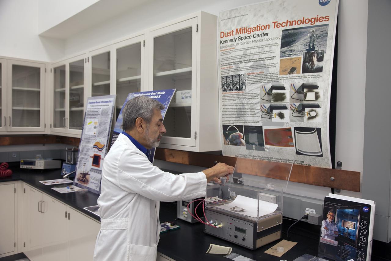 CAPE CANAVERAL, Fla. -- Dr. Carlos Calle, senior research scientist on the Electrodynamic Dust Shield for Dust Mitigation project, demonstrates equipment used in his experiments in the Electrostatics and Surface Physics Laboratory in the SwampWorks at NASA's Kennedy Space Center in Florida.      Electrodynamic dust shield, or EDS, technology is based on concepts originally developed by NASA as early as 1967 and later by the University of Tokyo. In 2003, NASA, in collaboration with the University of Arkansas at Little Rock, started development of the EDS for dust particle removal from solar panels to be used on future missions to the moon, an asteroid or Mars. A flight experiment to expose the dust shields to the space environment currently is under development. For more information, visit: http://www.nasa.gov/content/scientists-developing-ways-to-mitigate-dust-problem-for-explorers/ Photo credit: NASA/Dan Casper