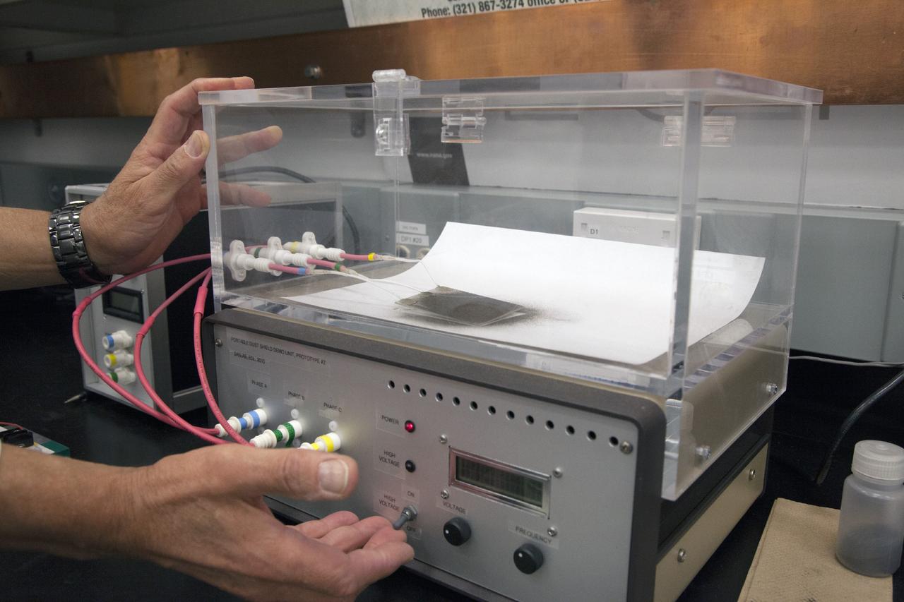 CAPE CANAVERAL, Fla. -- Dr. Carlos Calle, senior research scientist on the Electrodynamic Dust Shield for Dust Mitigation project, demonstrates a dust particle experiment in the Electrostatics and Surface Physics Laboratory in the SwampWorks at NASA's Kennedy Space Center in Florida. The technology works by creating an electric field that propagates out like the ripples on a pond. This could prevent dust accumulation on spacesuits, thermal radiators, solar panels, optical instruments and view ports for future lunar and Mars exploration activities.      Electrodynamic dust shield, or EDS, technology is based on concepts originally developed by NASA as early as 1967 and later by the University of Tokyo. In 2003, NASA, in collaboration with the University of Arkansas at Little Rock, started development of the EDS for dust particle removal from solar panels to be used on future missions to the moon, an asteroid or Mars. A flight experiment to expose the dust shields to the space environment currently is under development. For more information, visit: http://www.nasa.gov/content/scientists-developing-ways-to-mitigate-dust-problem-for-explorers/ Photo credit: NASA/Dan Casper